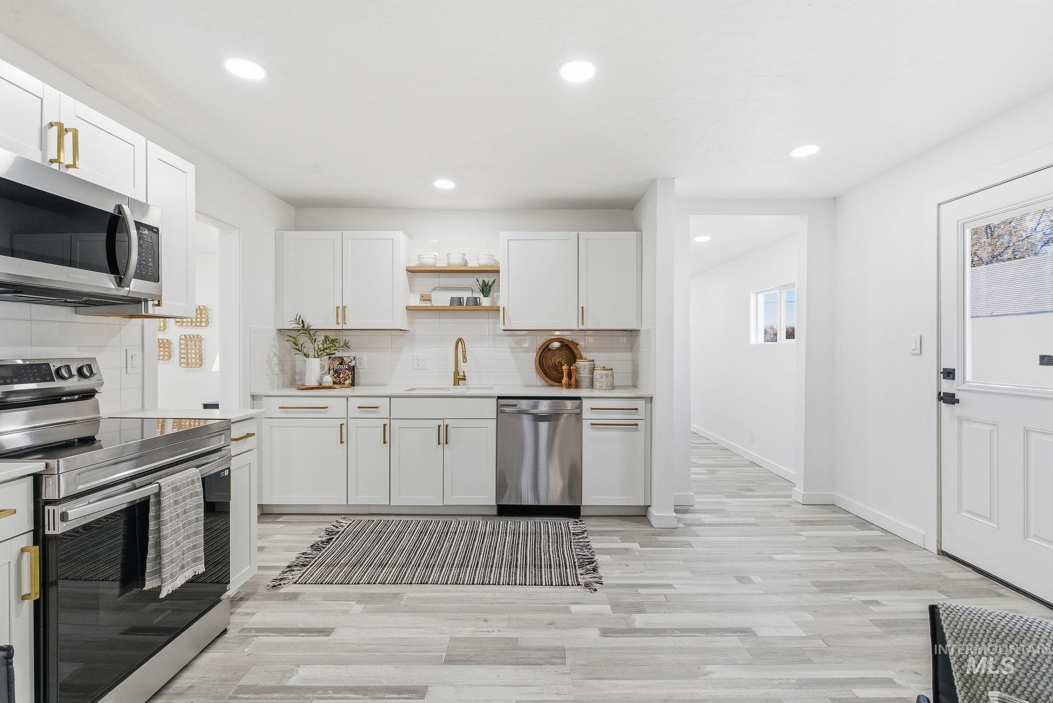 Kitchen with stainless steel appliances, tasteful backsplash, open shelves, recessed lighting, and white cabinetry