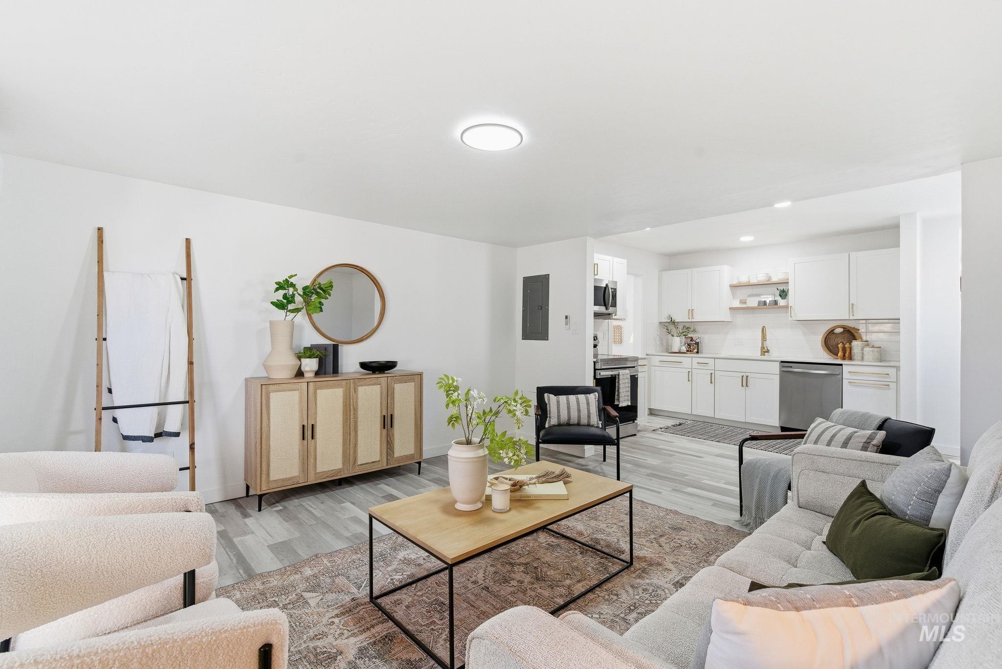 Living room featuring light wood-style flooring, electric panel, and recessed lighting
