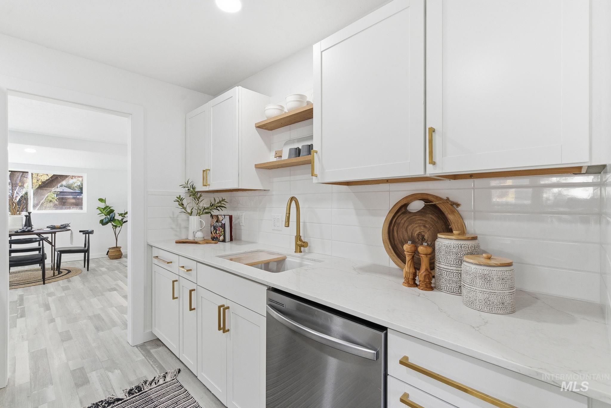 Kitchen featuring open shelves, stainless steel dishwasher, light stone counters, tasteful backsplash, and white cabinets