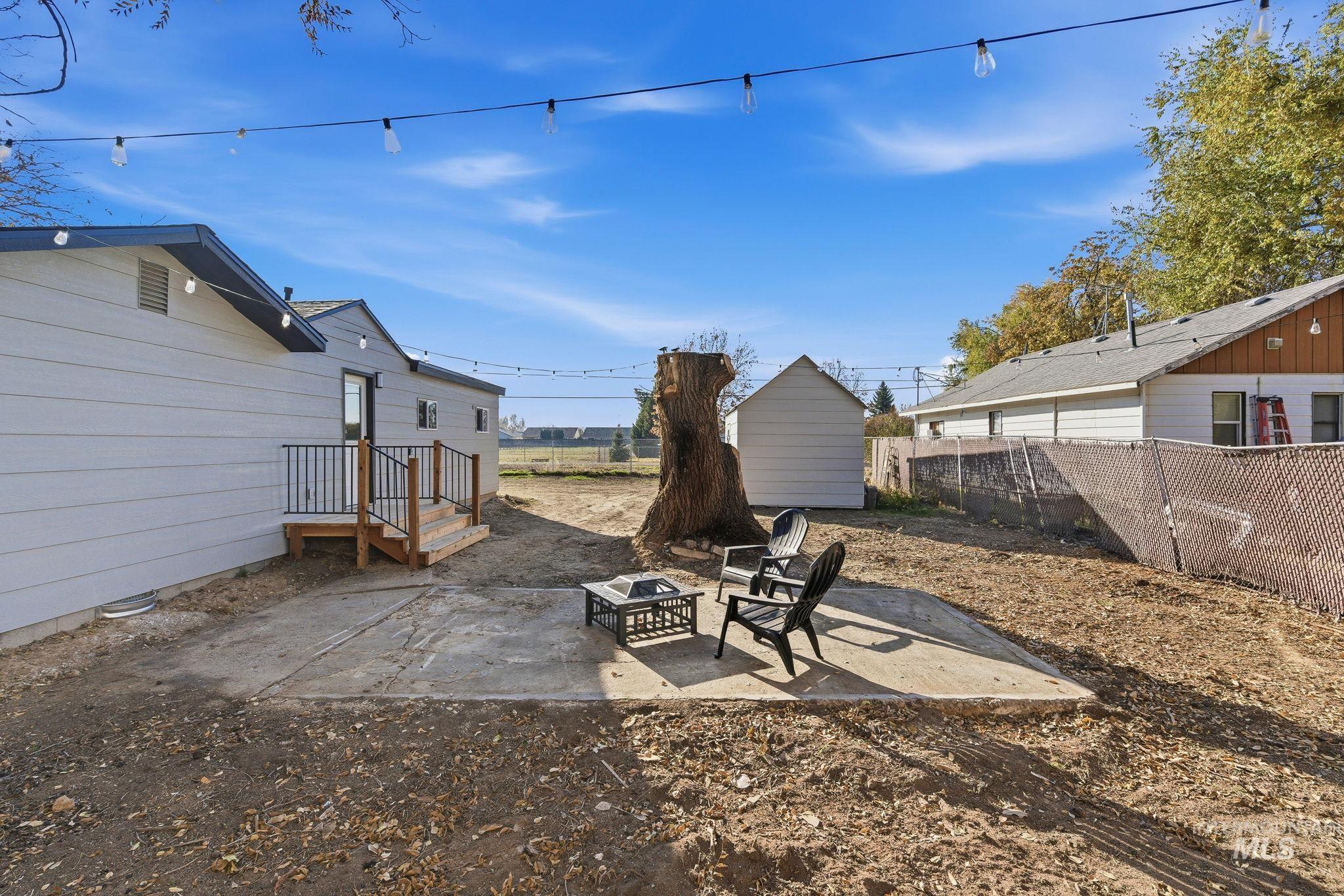 Fenced backyard with a patio, an outdoor fire pit, and a storage unit