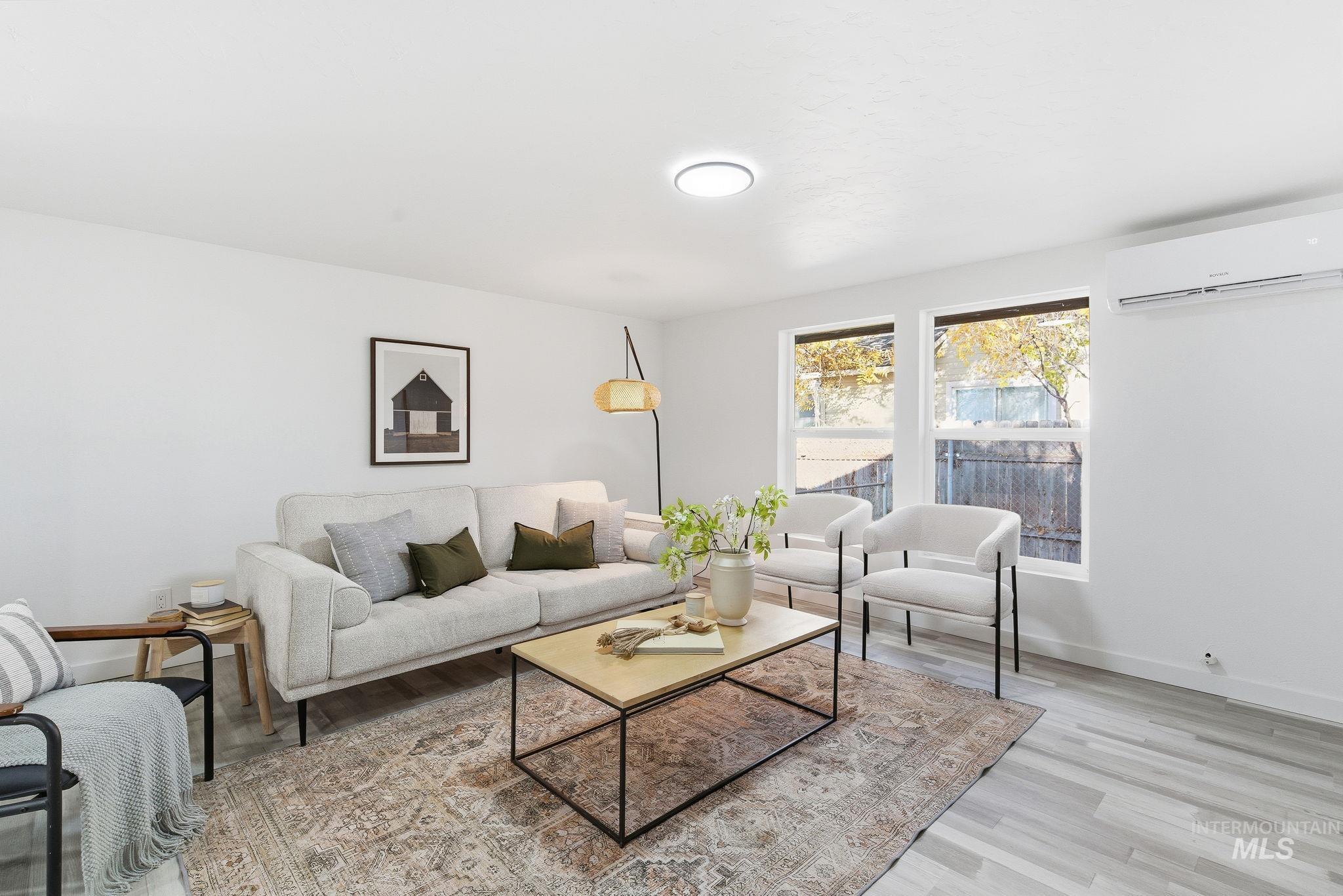 Living area featuring light wood-style floors and an AC wall unit