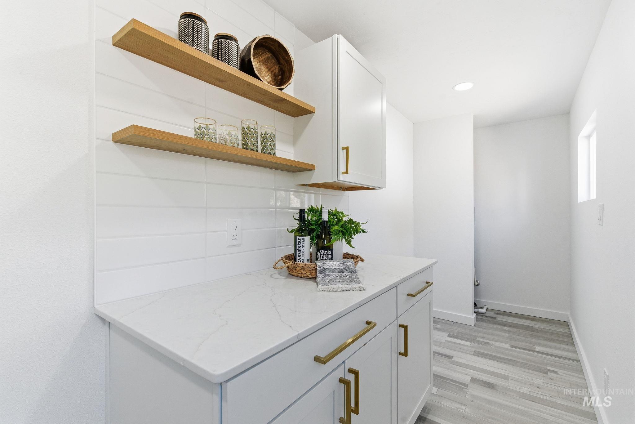 Bar featuring light stone counters, tasteful backsplash, white cabinetry, light wood finished floors, and recessed lighting