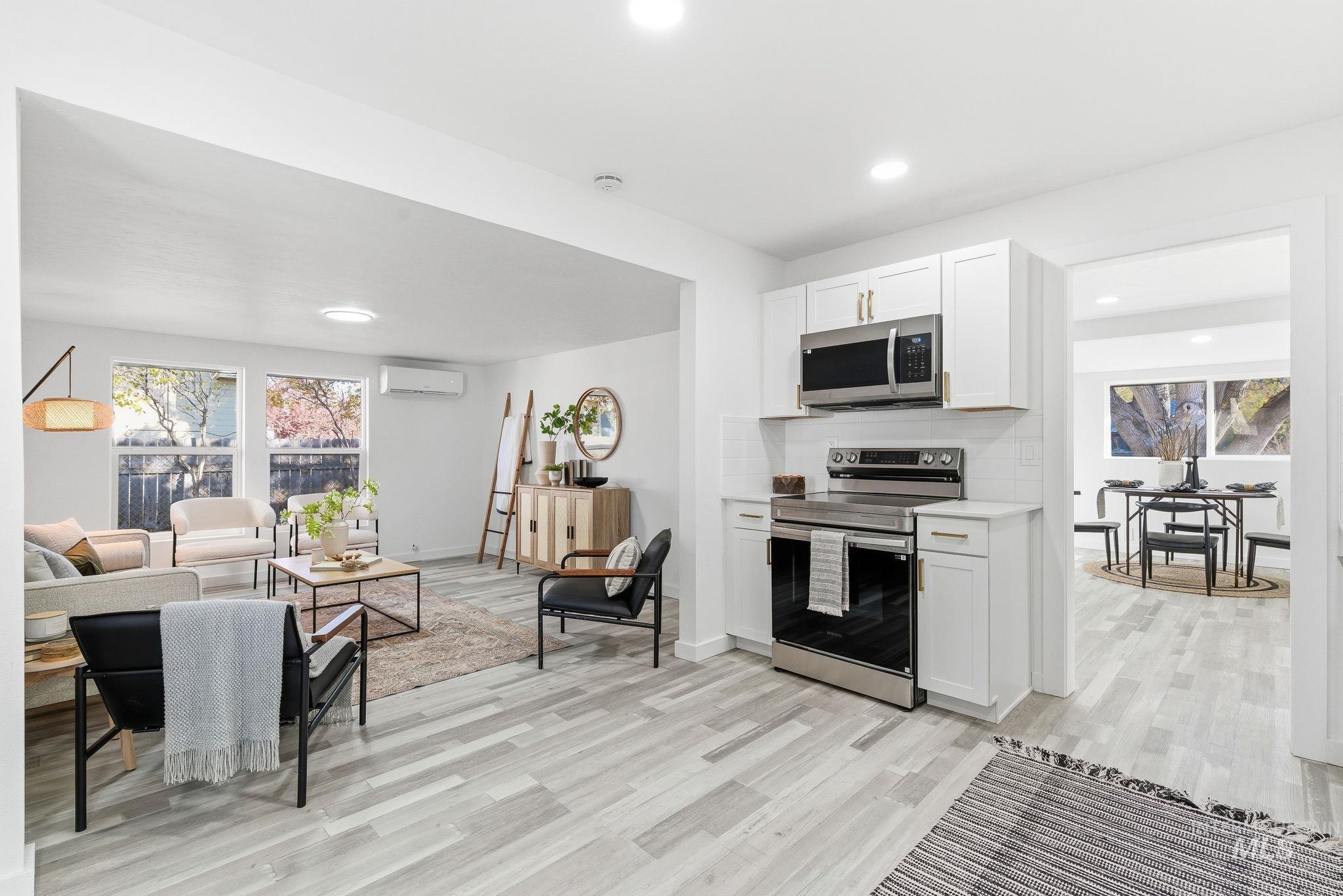 Kitchen with white cabinets, appliances with stainless steel finishes, light wood-type flooring, decorative backsplash, and recessed lighting