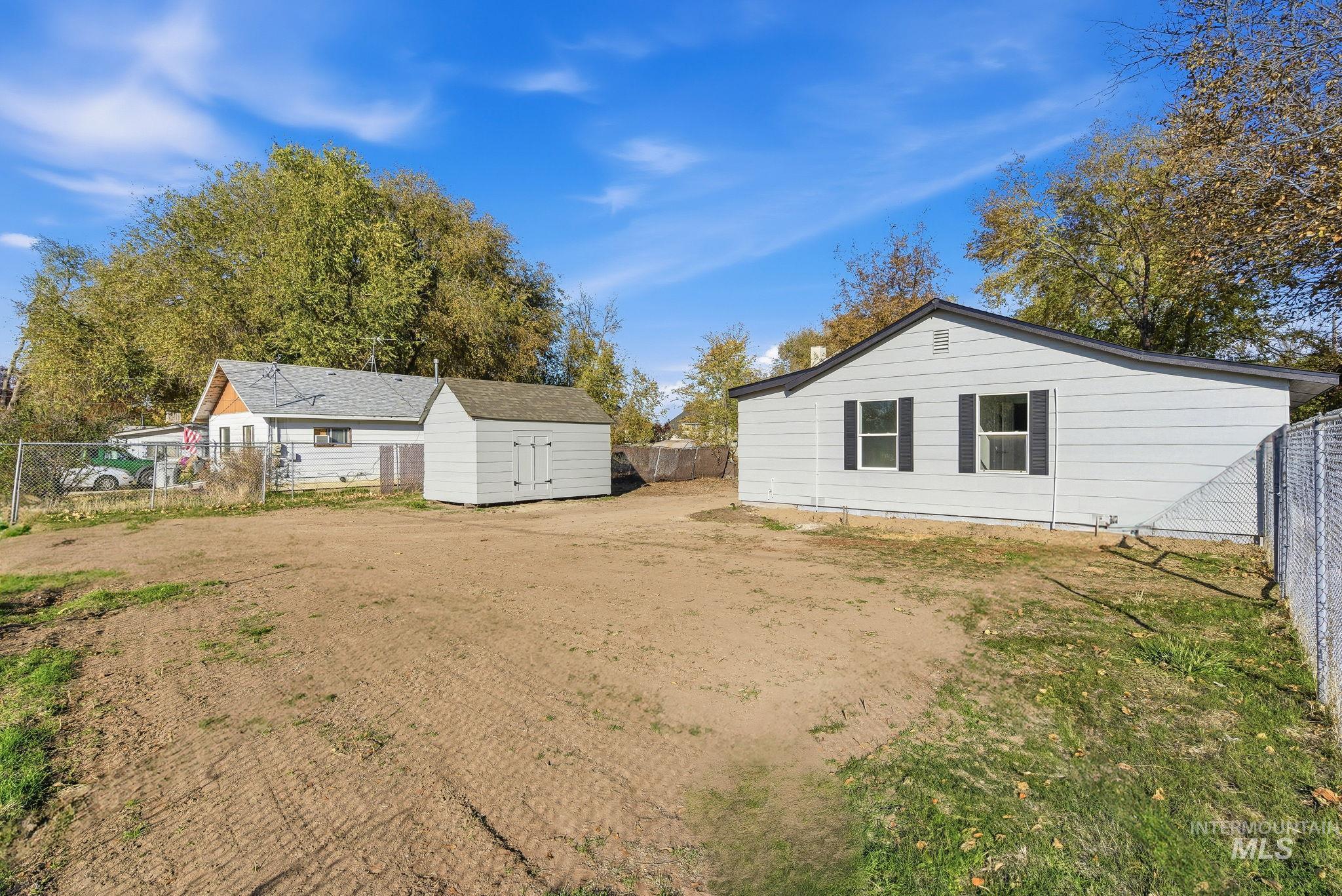 Back of house with a fenced backyard, a storage shed, and dirt driveway