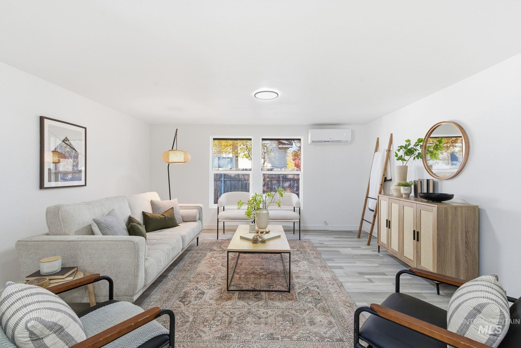 Living room with light wood finished floors and a wall unit AC