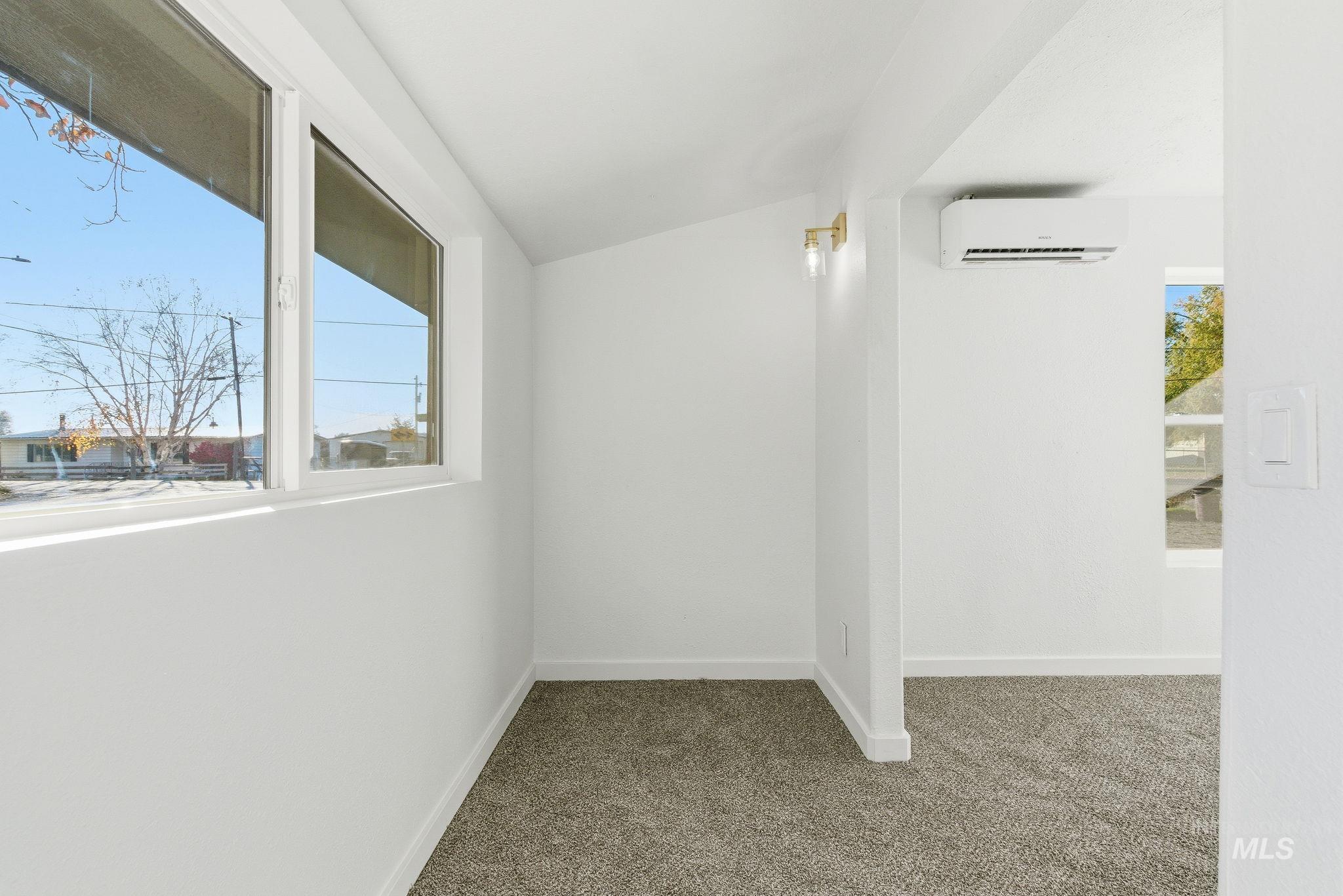 Carpeted spare room with lofted ceiling and a wall unit AC