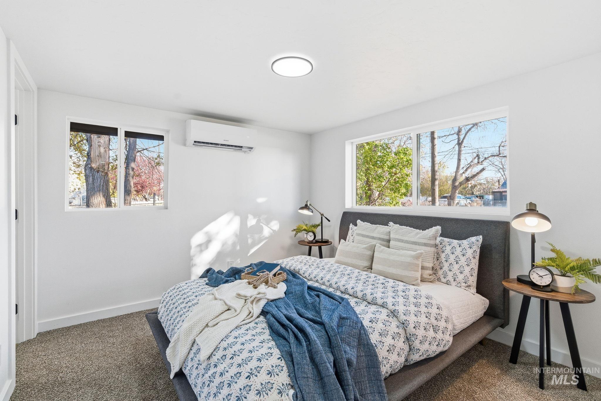 Carpeted bedroom with baseboards and an AC wall unit