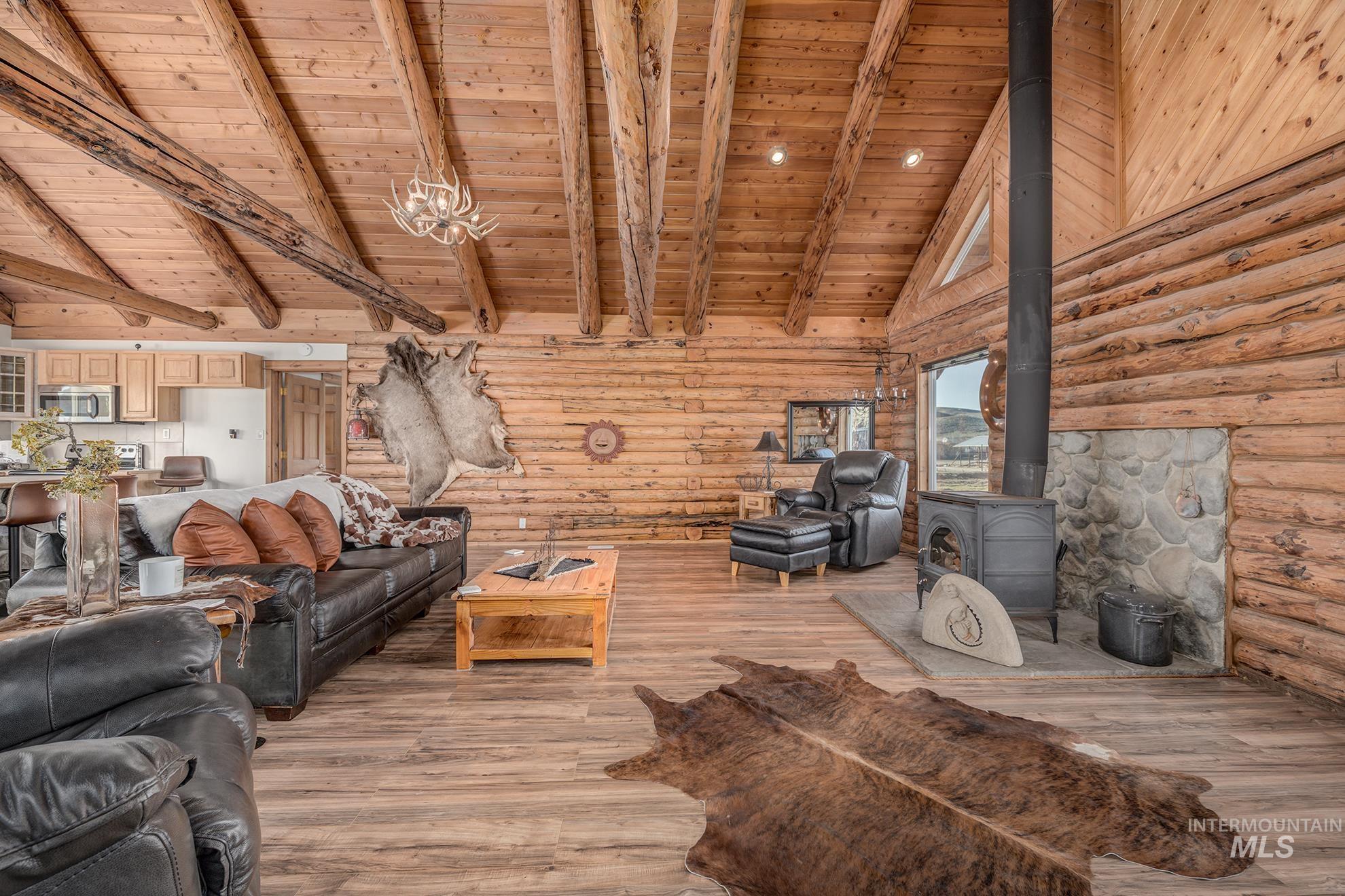 Living area featuring a wood stove, a high wooden beamed ceiling, light wood-style floors, and log walls