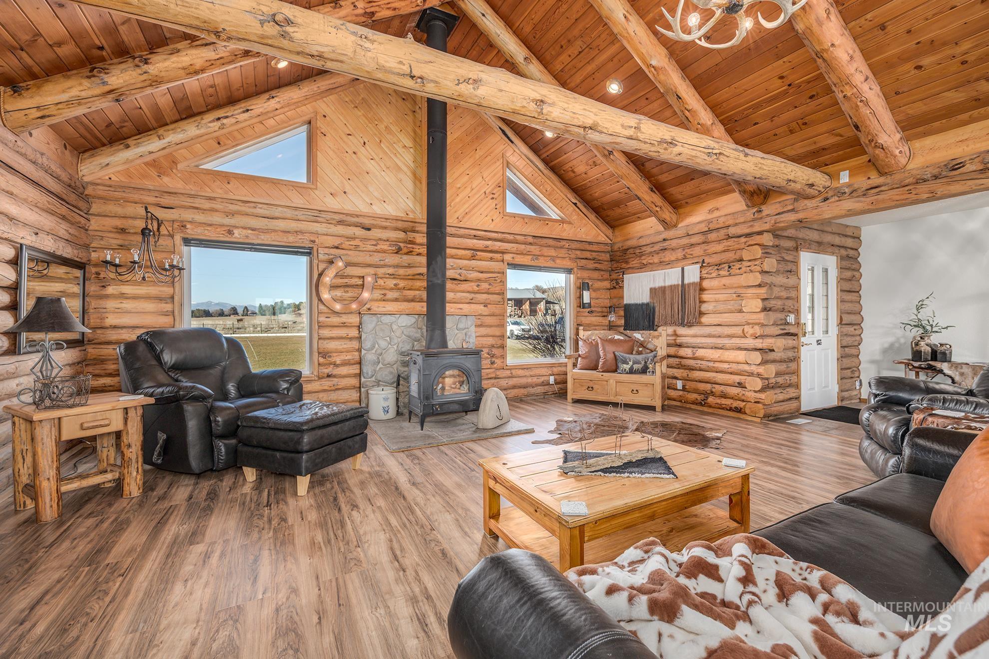 Living area featuring a wood stove, wood-type flooring, a high wood beamed ceiling, and rustic walls