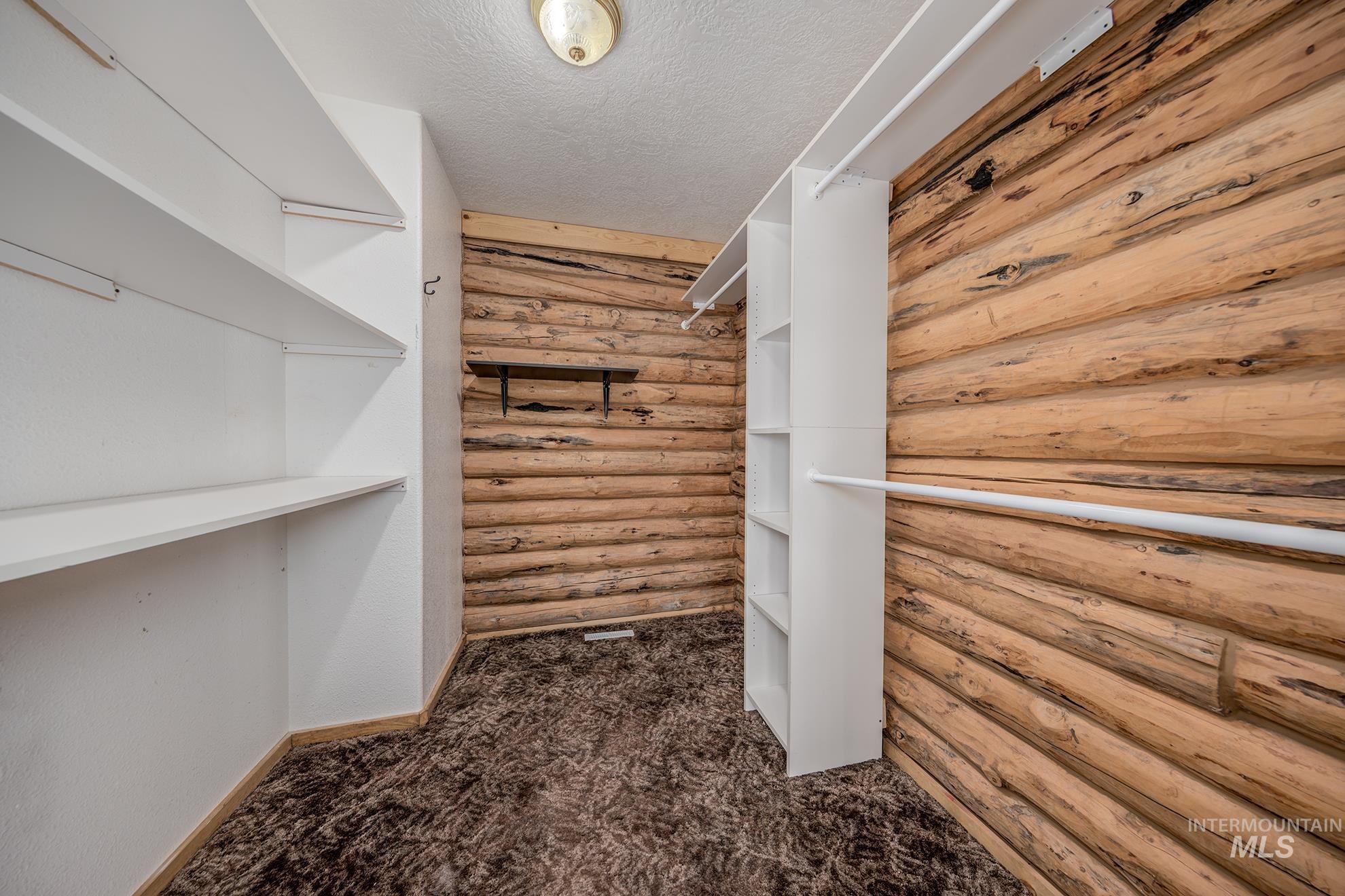 Walk in closet with dark colored carpet