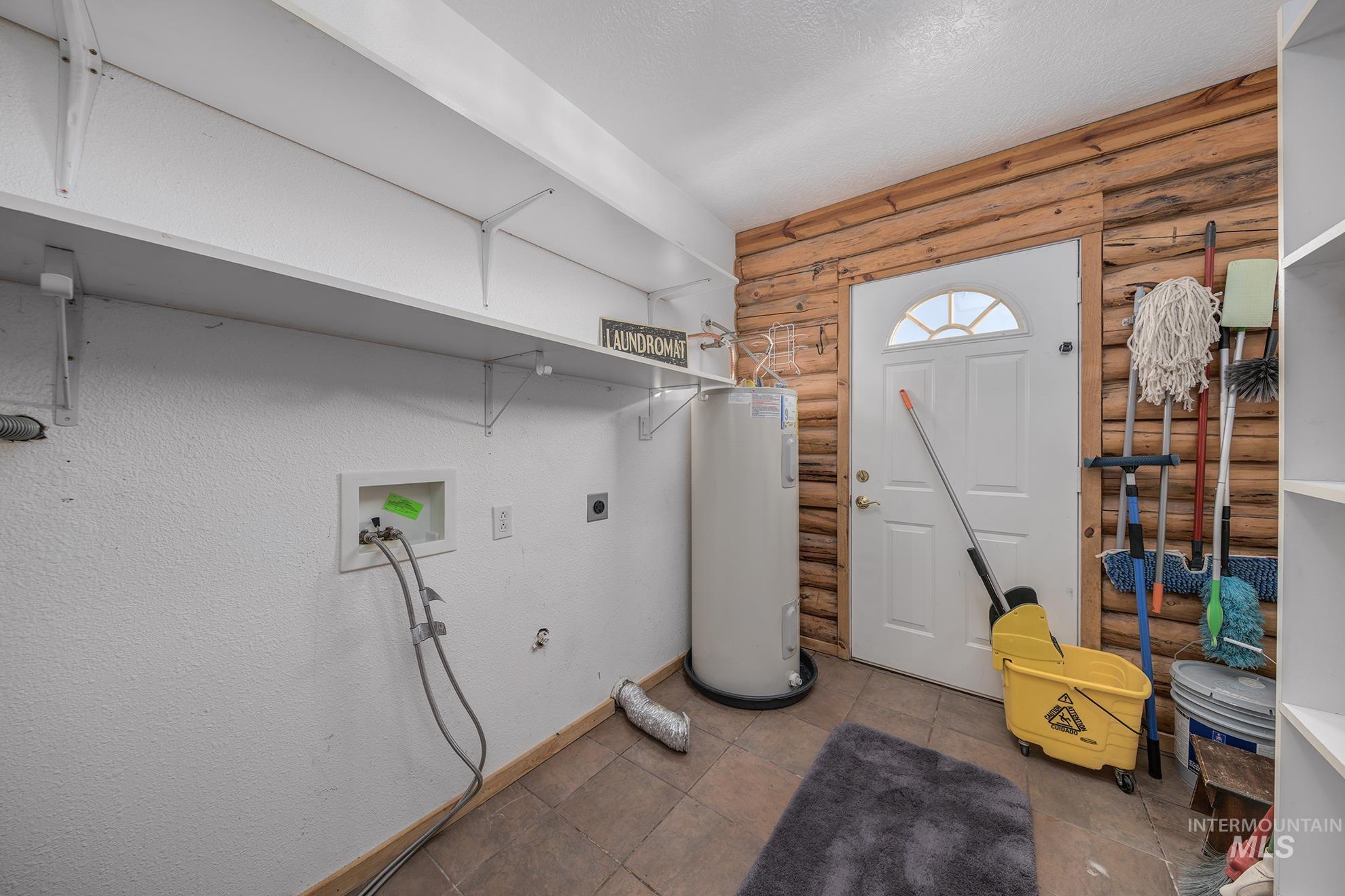 Laundry area featuring log walls, hookup for an electric dryer, water heater, washer hookup, and a textured ceiling