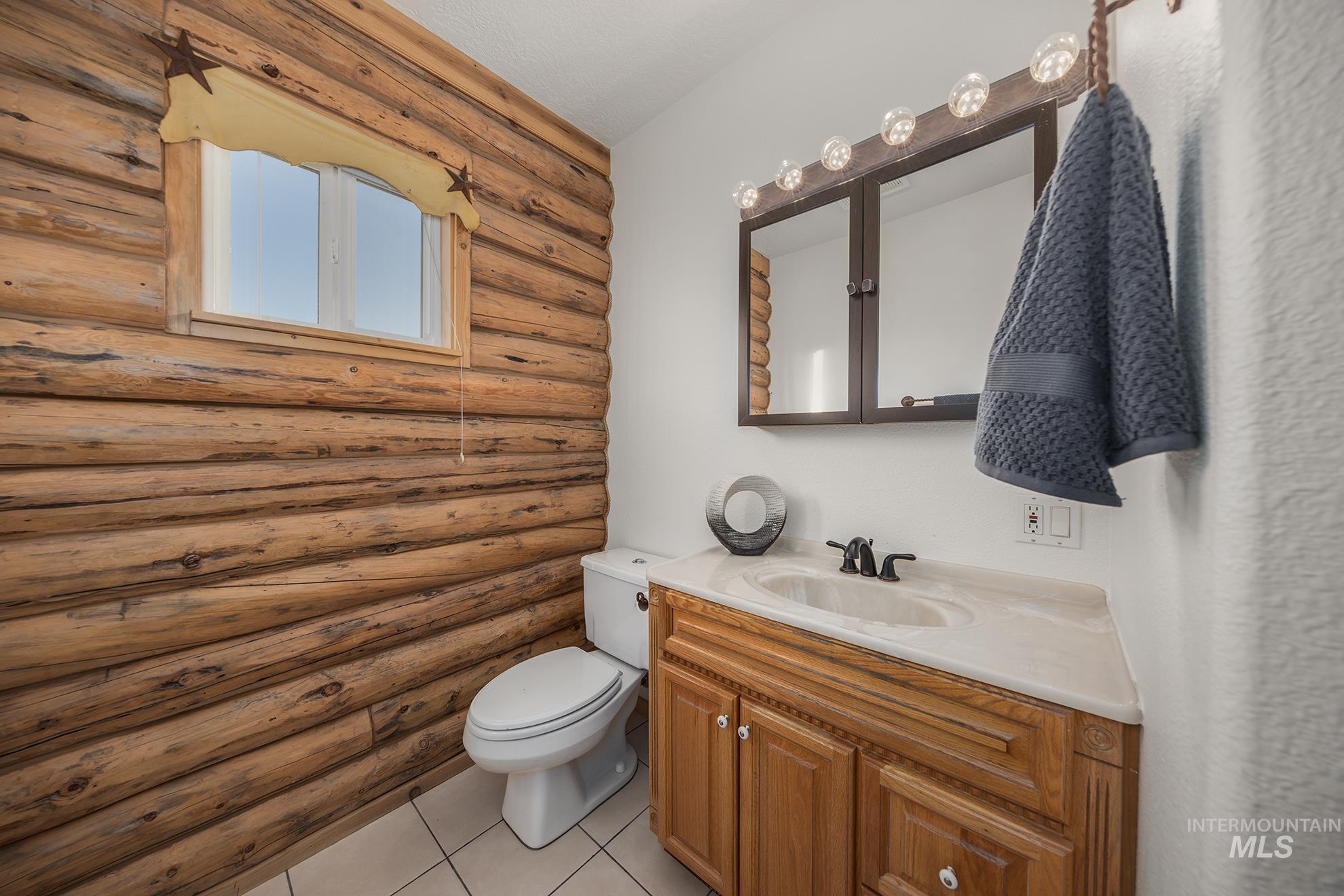 Half bathroom with vanity, rustic walls, and light tile patterned floors