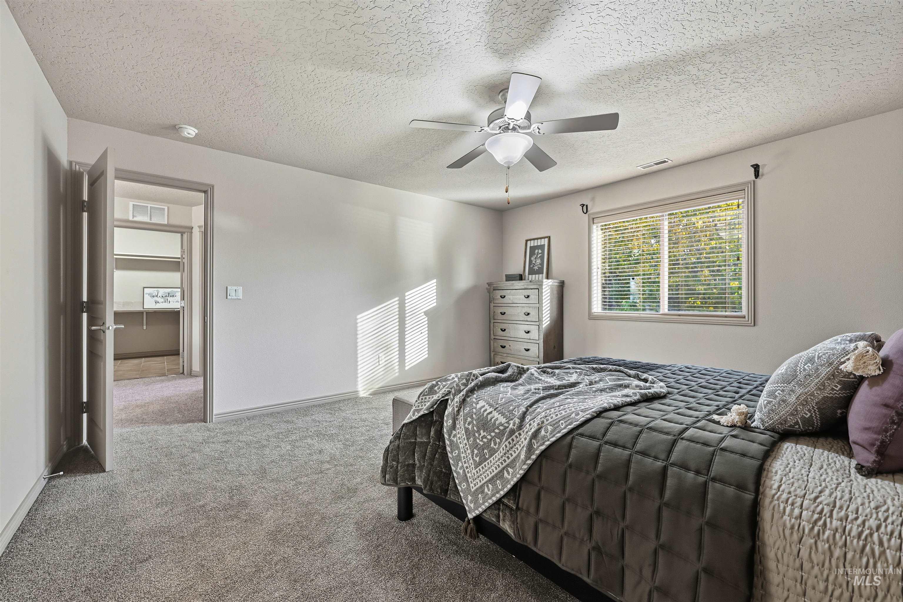 Carpeted bedroom with a textured ceiling and ceiling fan