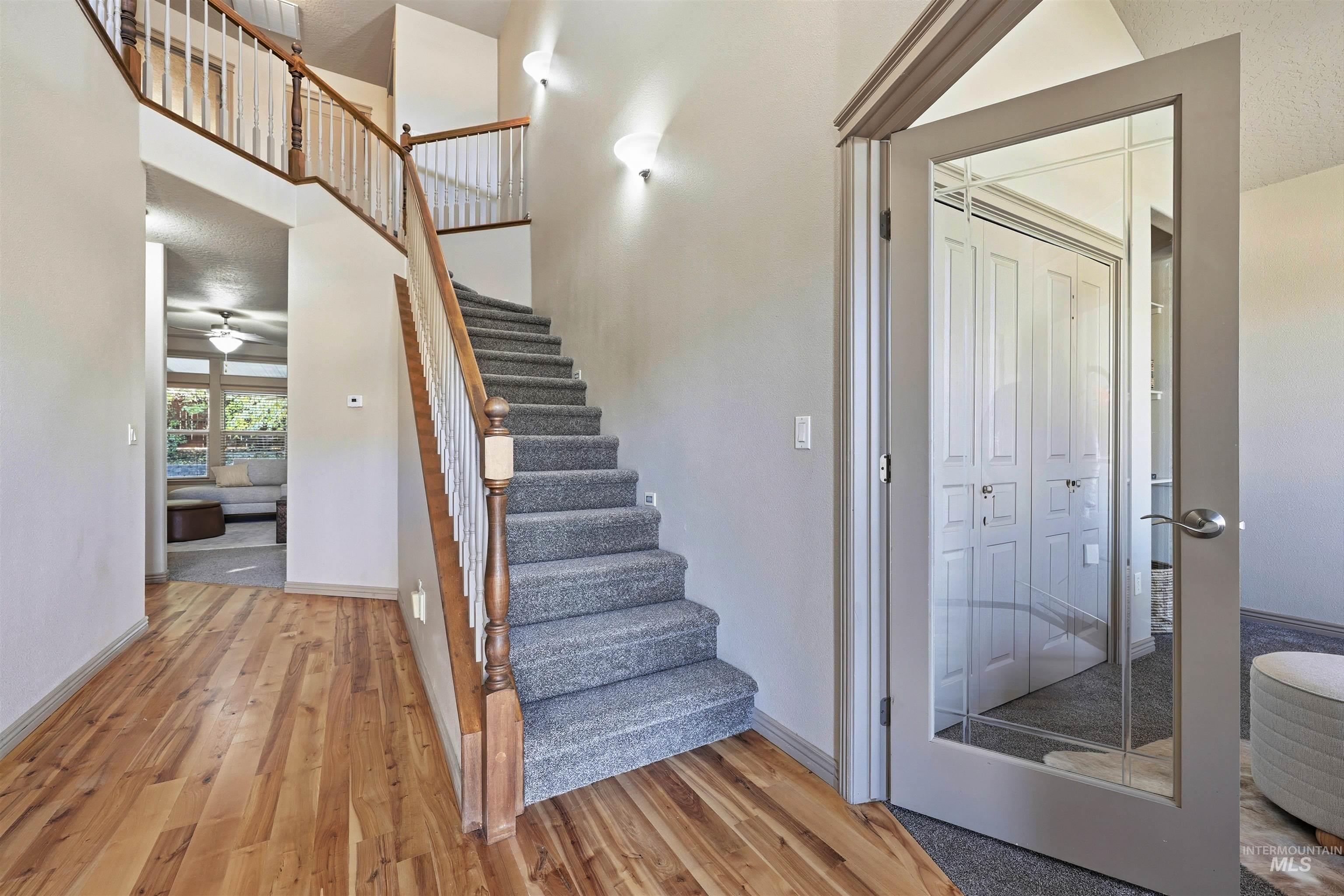 Stairs with a towering ceiling, wood finished floors, a textured ceiling, and a ceiling fan