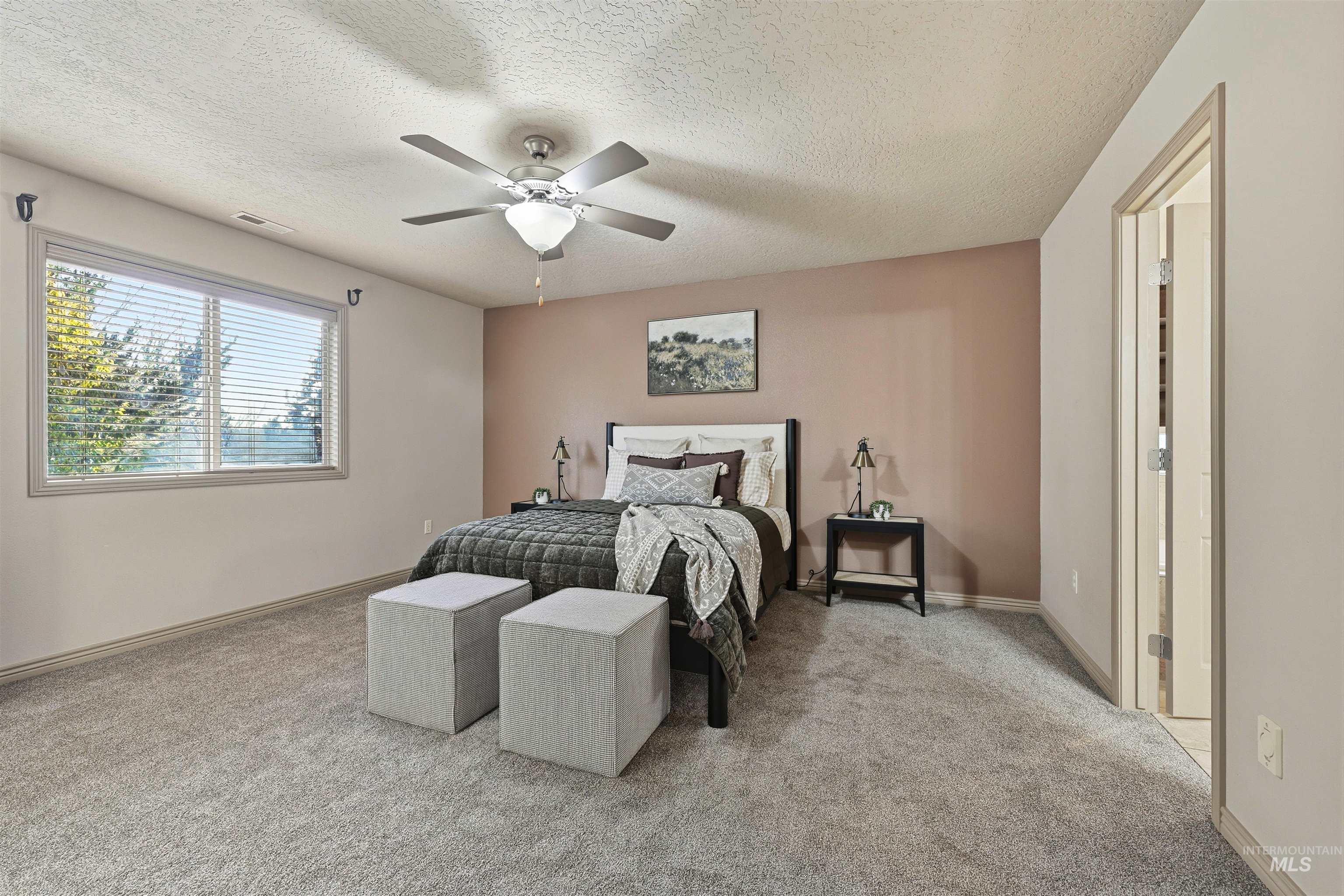 Bedroom featuring light colored carpet, a textured ceiling, and ceiling fan