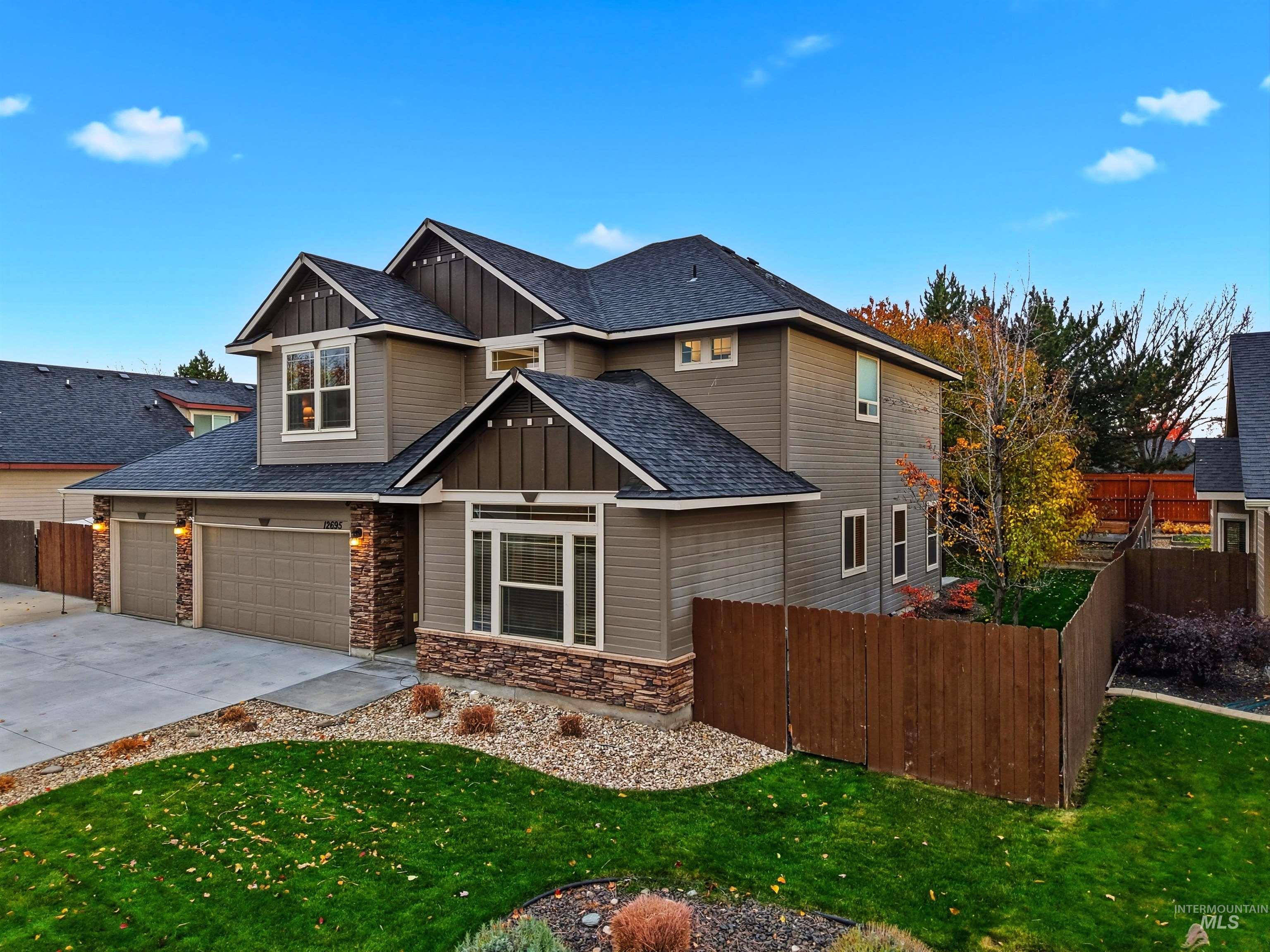 Craftsman house with board and batten siding, stone siding, roof with shingles, and driveway