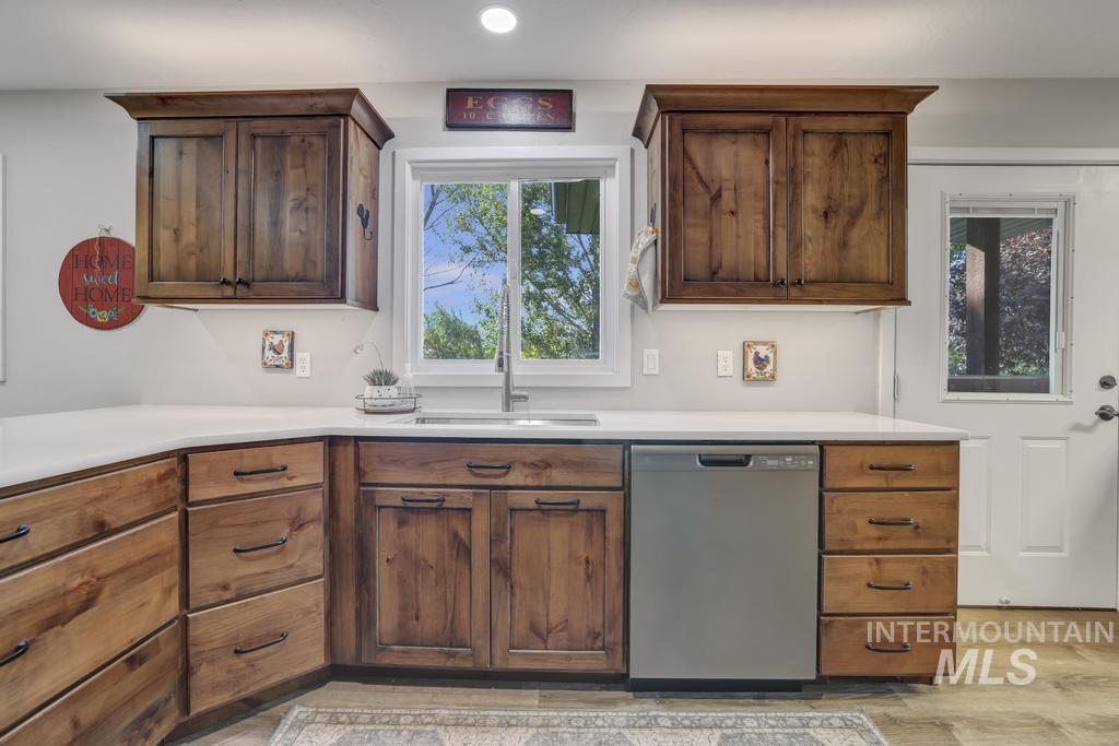 Kitchen with stainless steel dishwasher, light countertops, recessed lighting, and light wood-style floors