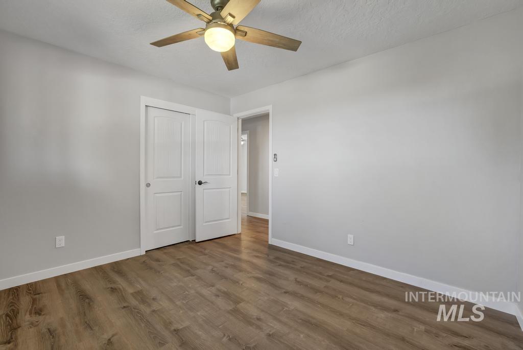 Unfurnished bedroom with wood finished floors, ceiling fan, a closet, and a textured ceiling