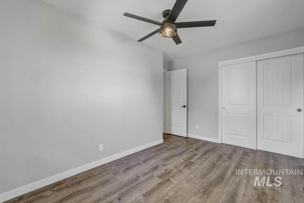 Unfurnished bedroom with wood finished floors, a closet, and a ceiling fan