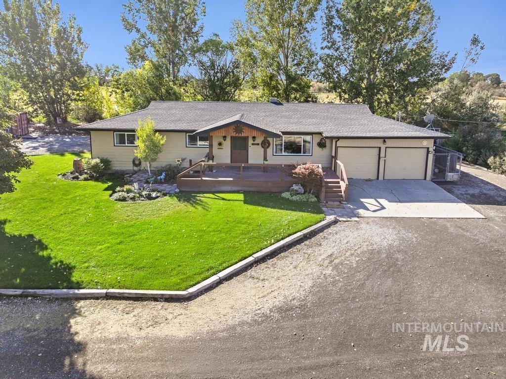Ranch-style home featuring driveway, a front lawn, covered porch, and an attached garage