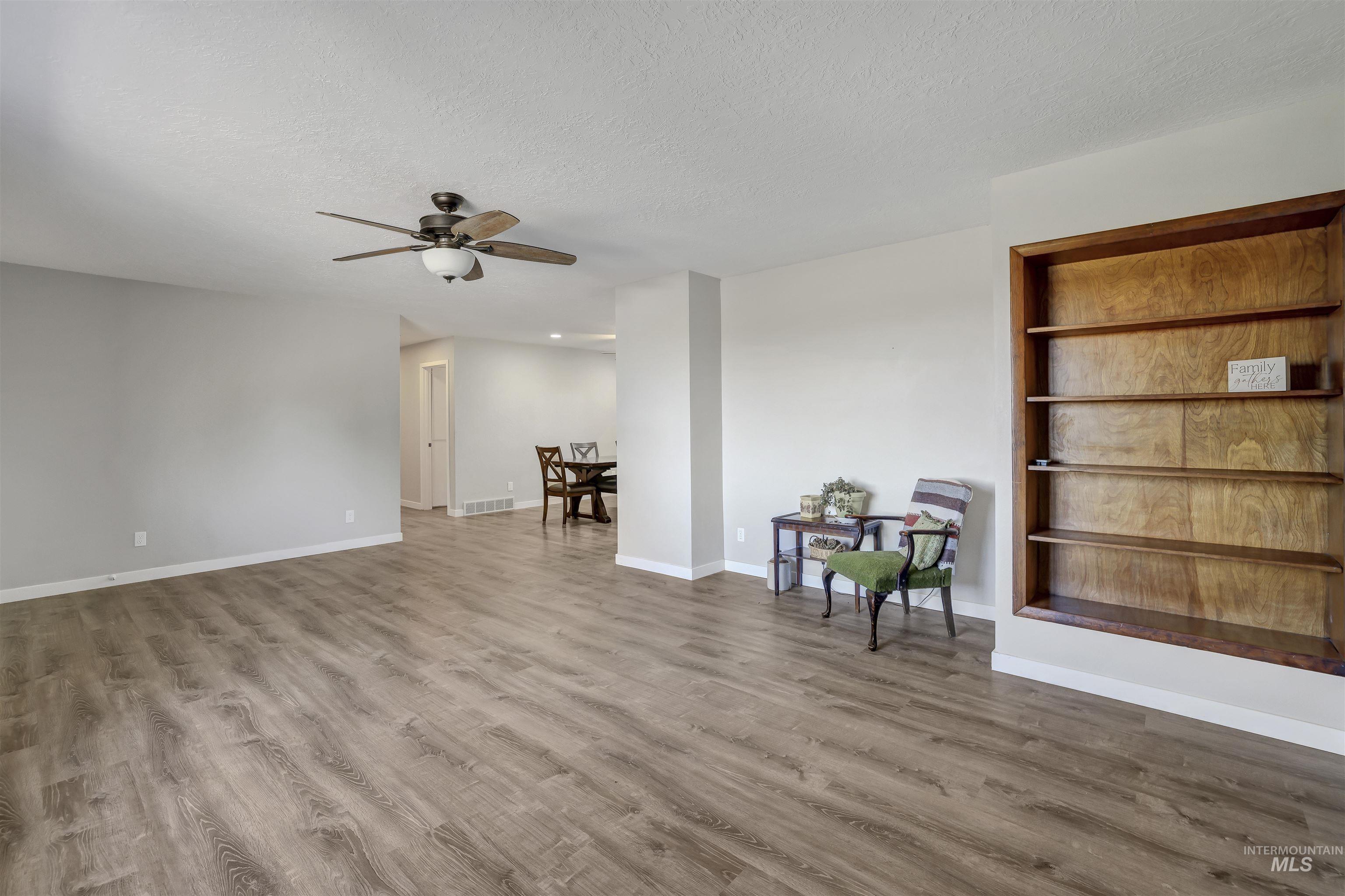 Living area with light wood-style flooring, a textured ceiling, and ceiling fan
