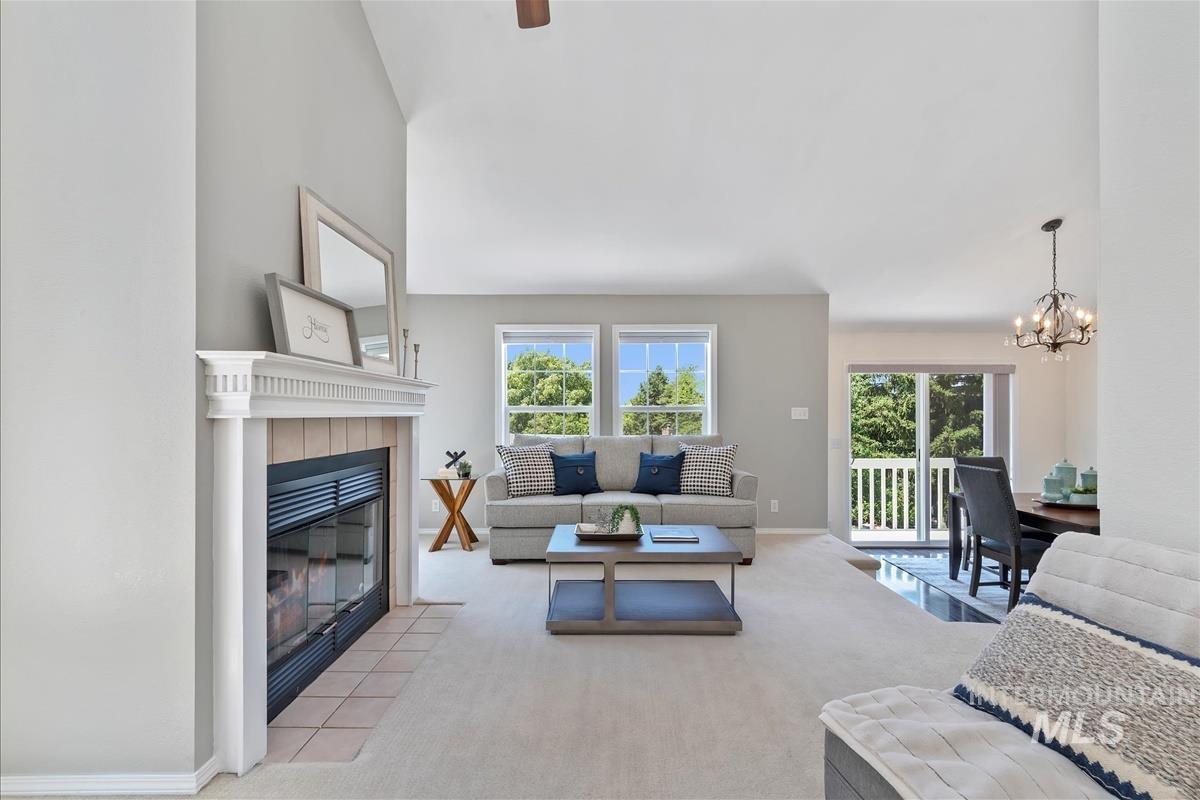 Carpeted living area with healthy amount of natural light, a chandelier, and a tile fireplace