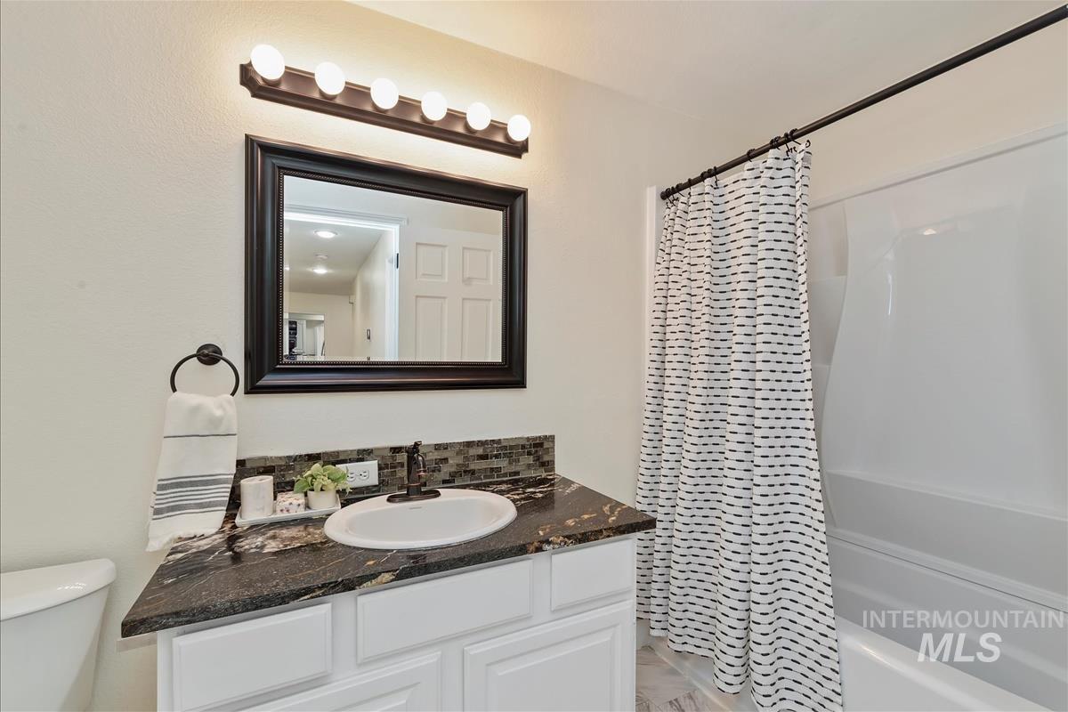 Full bath featuring vanity, shower / bathtub combination with curtain, and marble finish flooring