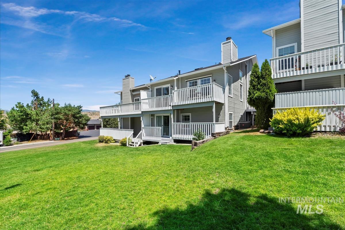 Back of property with a balcony, a chimney, and a lawn