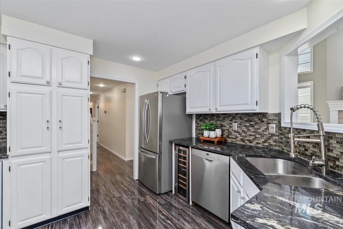 Kitchen featuring appliances with stainless steel finishes, white cabinets, backsplash, dark stone countertops, and recessed lighting