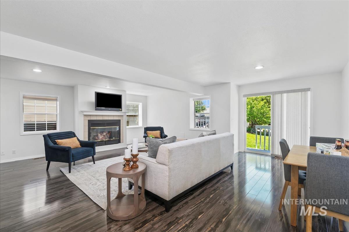 Living room with dark wood-type flooring, a tile fireplace, and recessed lighting