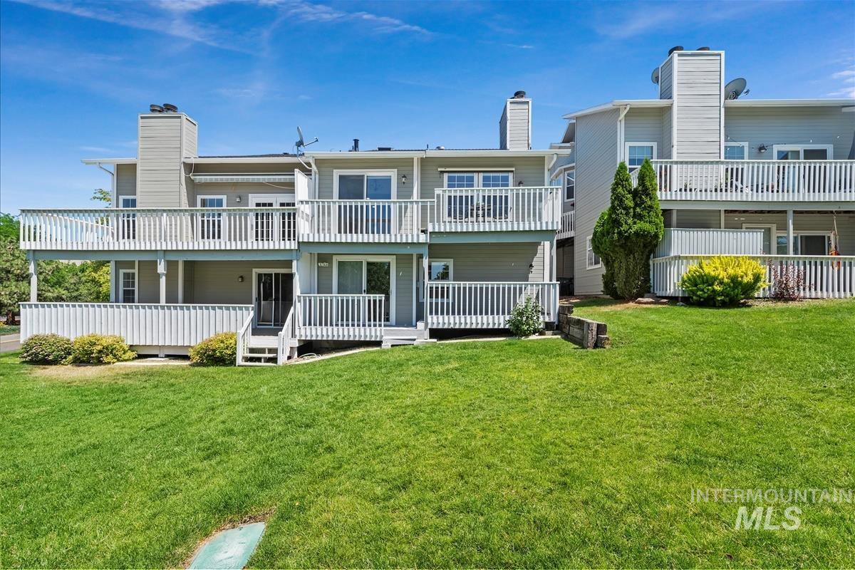 Back of house with a chimney, a yard, and a balcony