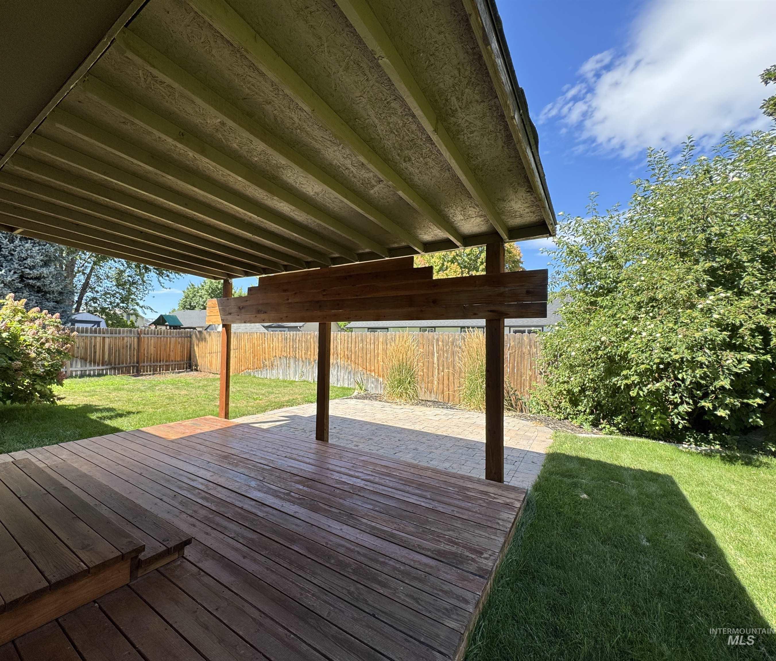 Wooden terrace with a fenced backyard and a patio area