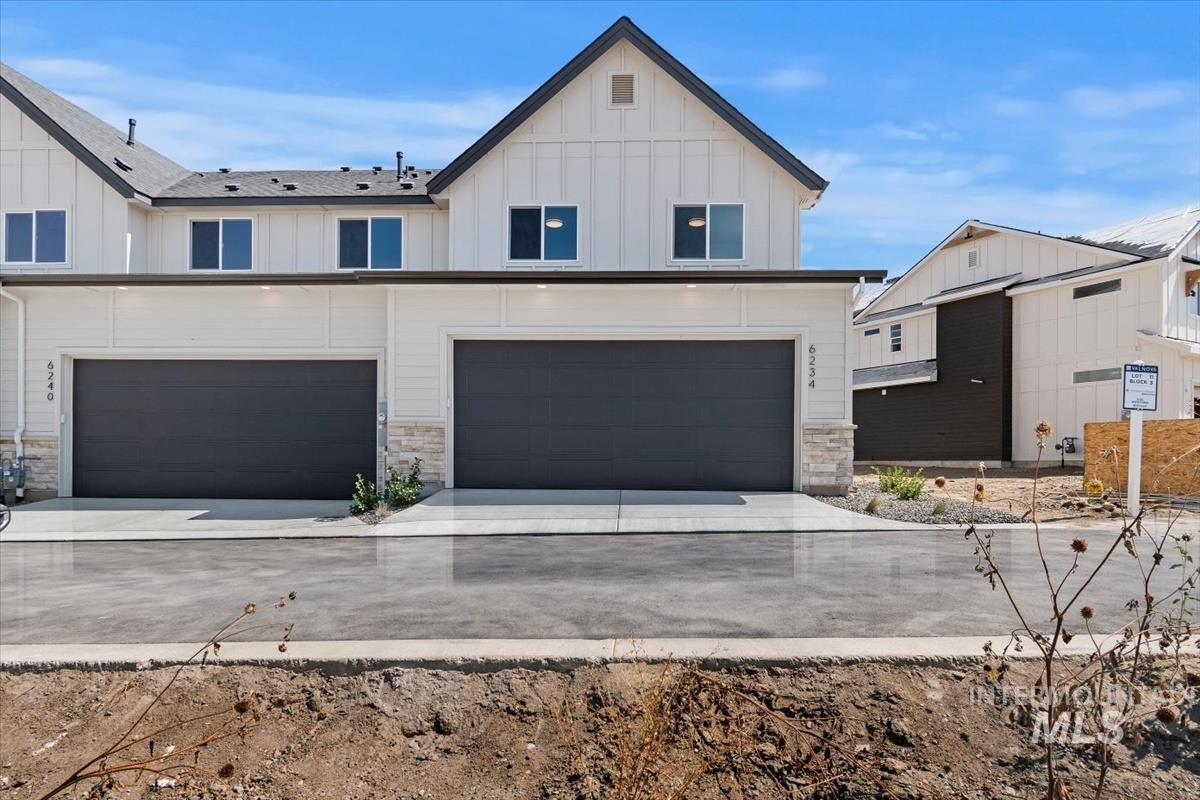 Modern farmhouse style home featuring board and batten siding, stone siding, an attached garage, and concrete driveway