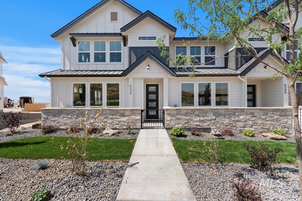 Modern farmhouse style home featuring a standing seam roof, a metal roof, a gate, and board and batten siding