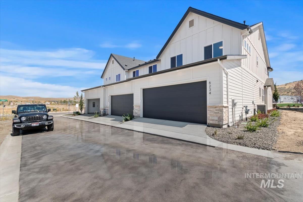 View of front of house with board and batten siding, stone siding, a mountain view, and driveway