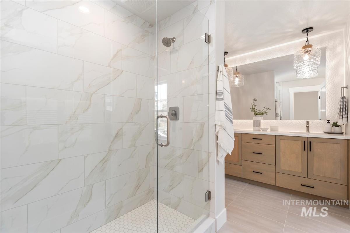 Full bath featuring vanity, a stall shower, and light tile patterned flooring