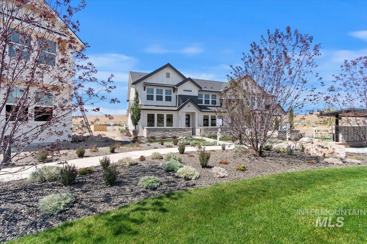 View of front of property featuring a front lawn, stone siding, a standing seam roof, and a metal roof
