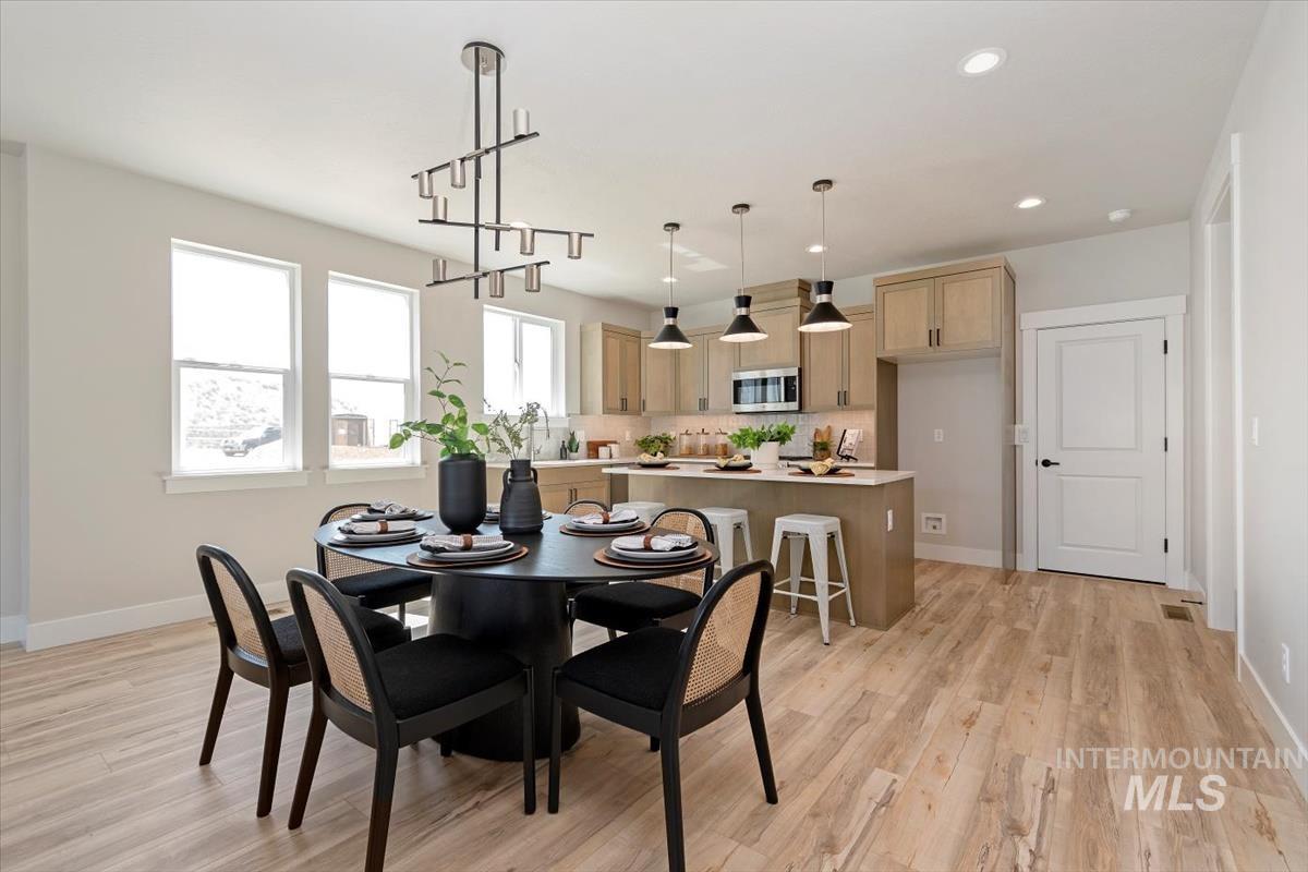 Dining area with recessed lighting, light wood-style floors, and a chandelier