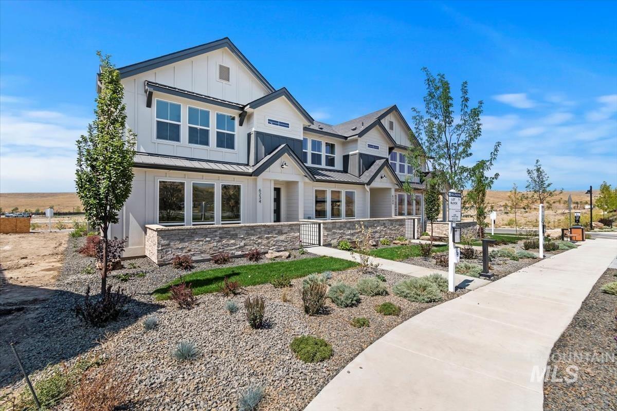 View of front of property featuring board and batten siding, a standing seam roof, a metal roof, and stone siding