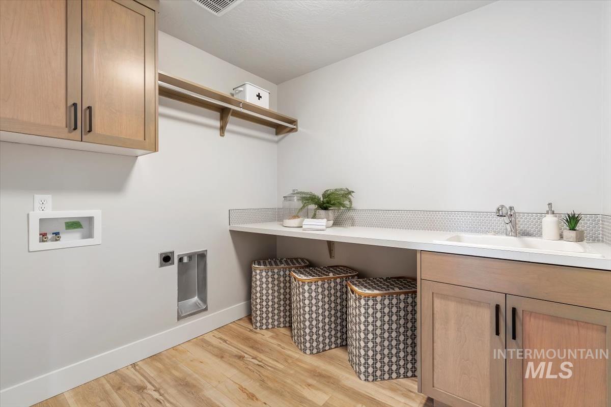 Laundry room with cabinet space, light wood-style flooring, hookup for an electric dryer, and washer hookup