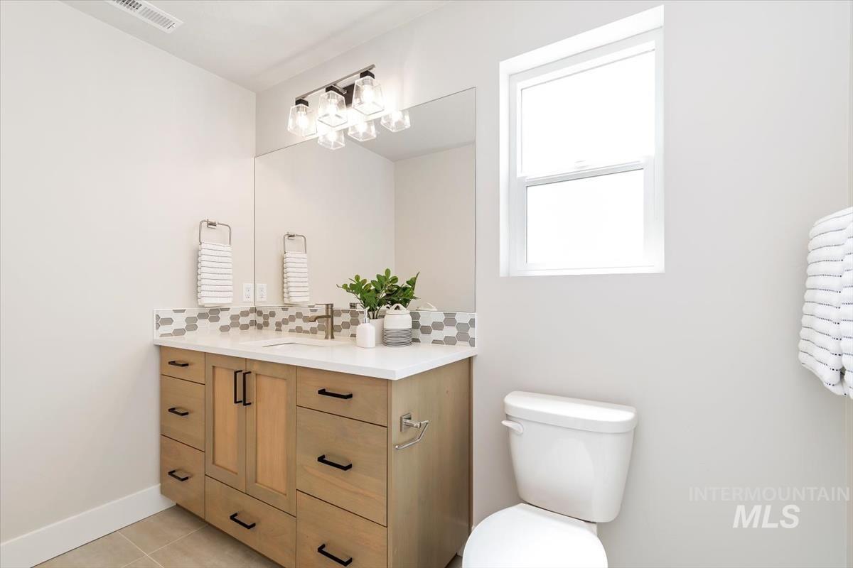 Bathroom featuring vanity, tasteful backsplash, and light tile patterned floors
