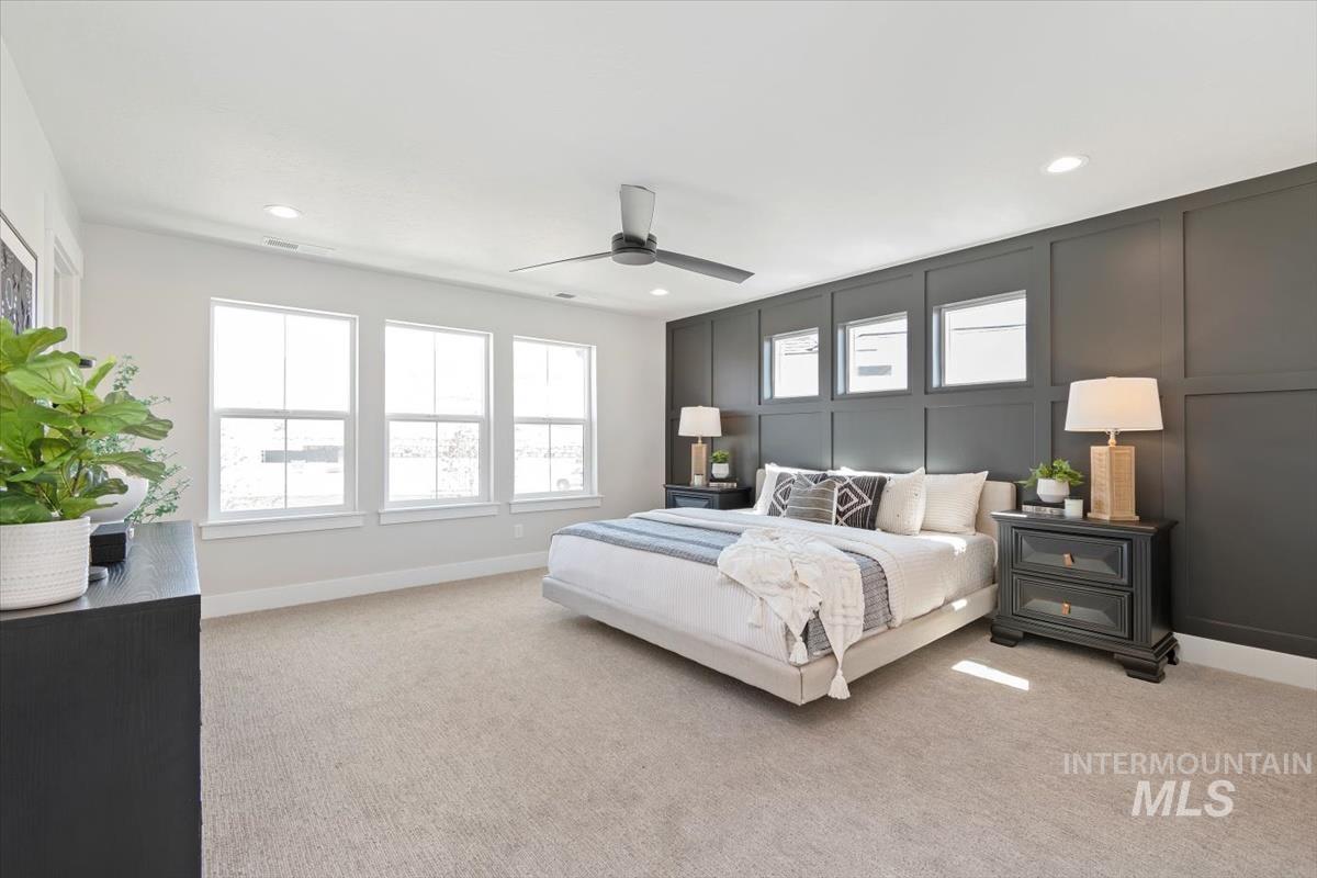 Bedroom featuring a decorative wall, light colored carpet, ceiling fan, and recessed lighting