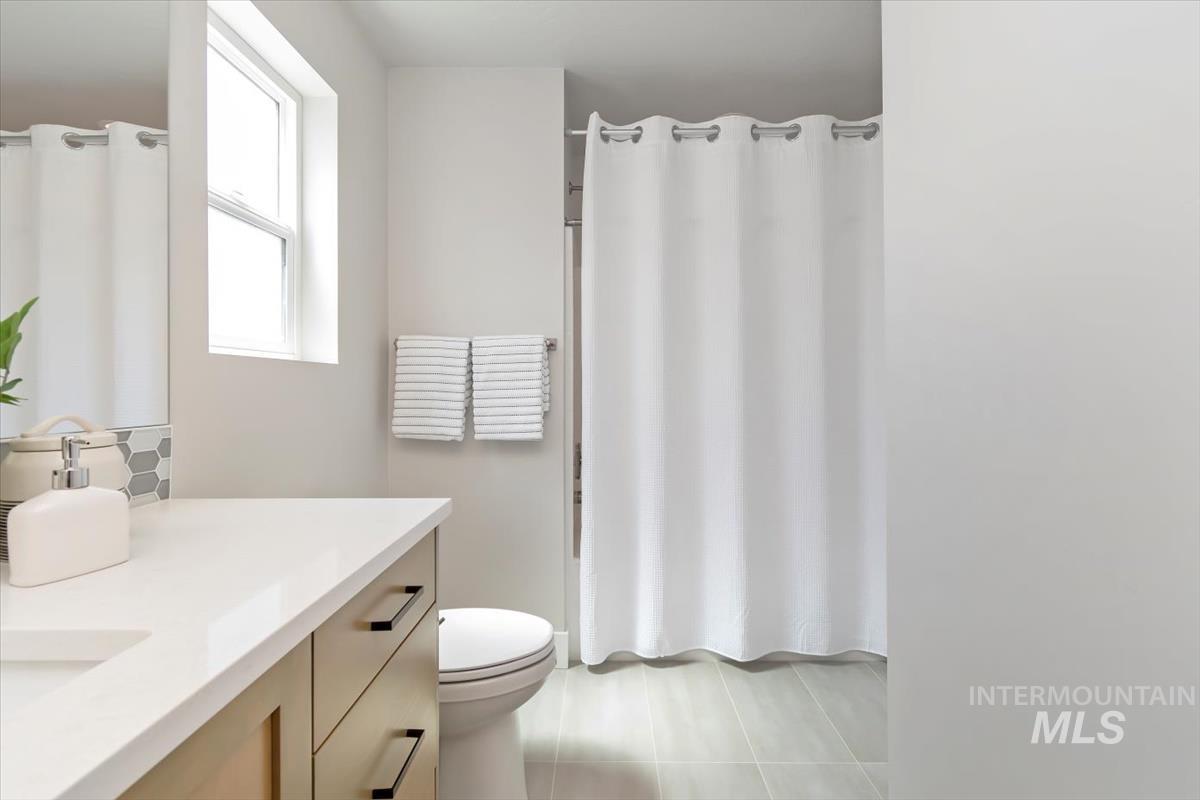 Full bath featuring vanity, light tile patterned floors, and decorative backsplash