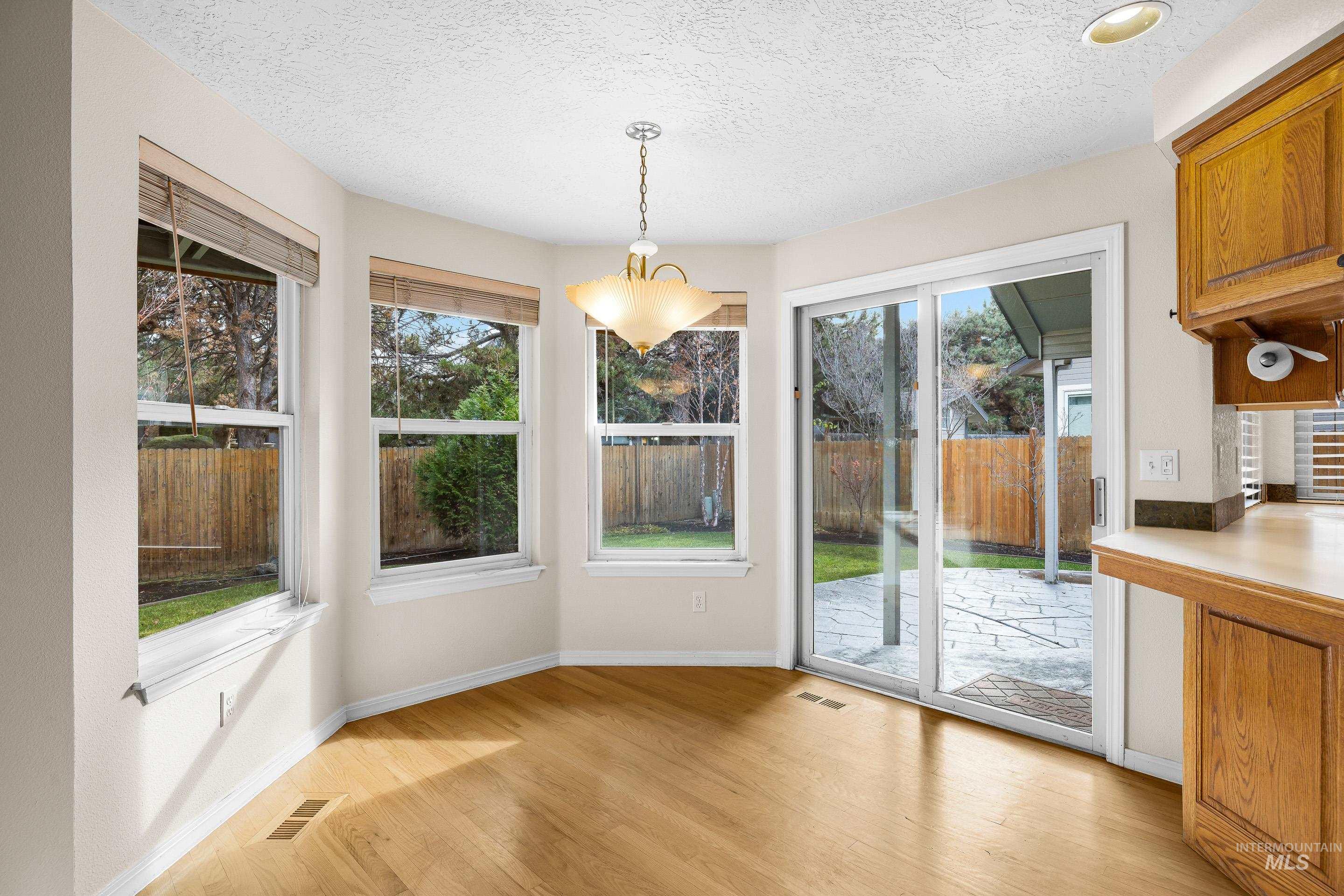 Unfurnished dining area featuring light wood-style floors, plenty of natural light, and a textured ceiling