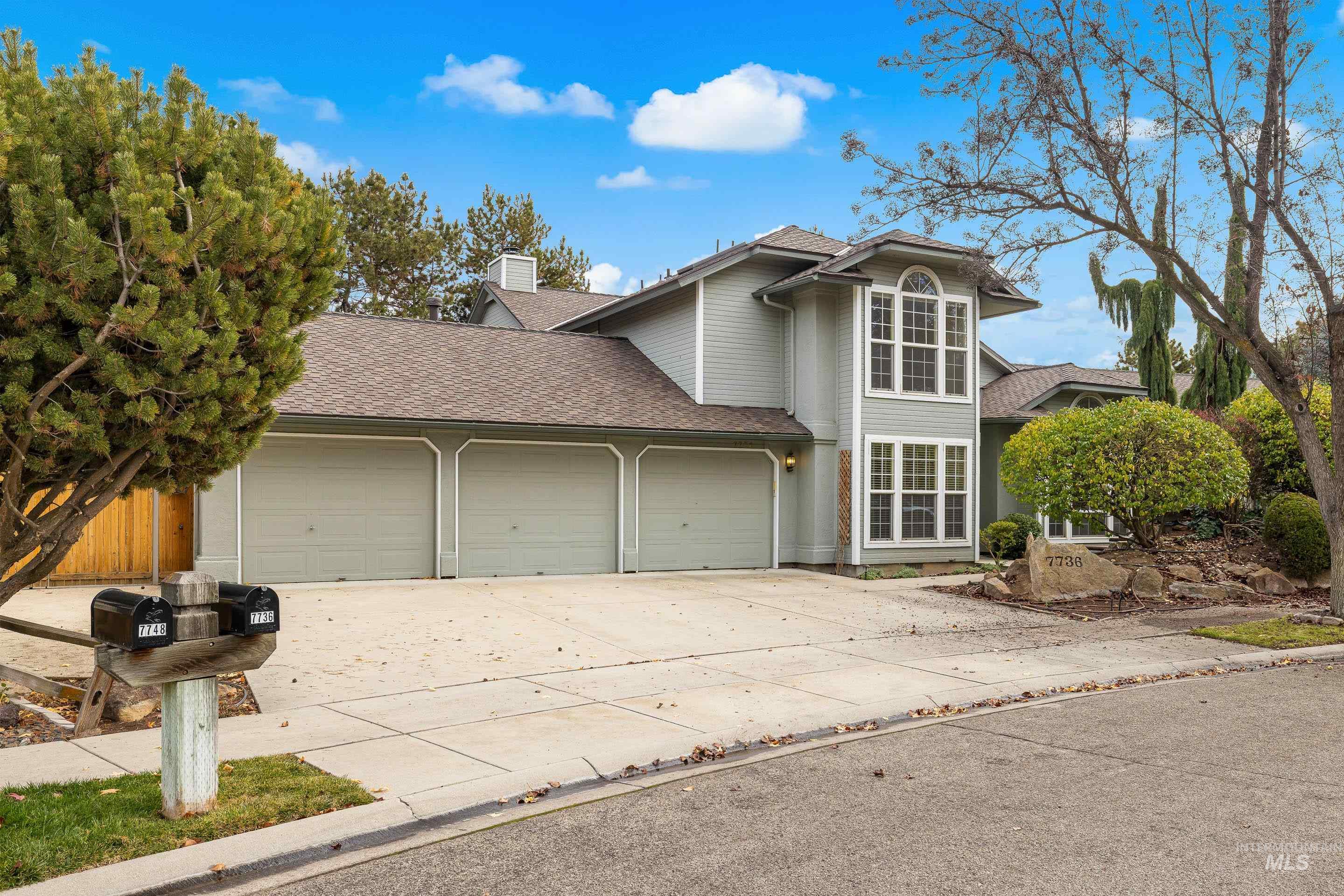 Traditional home featuring a shingled roof, concrete driveway, an attached garage, and a chimney