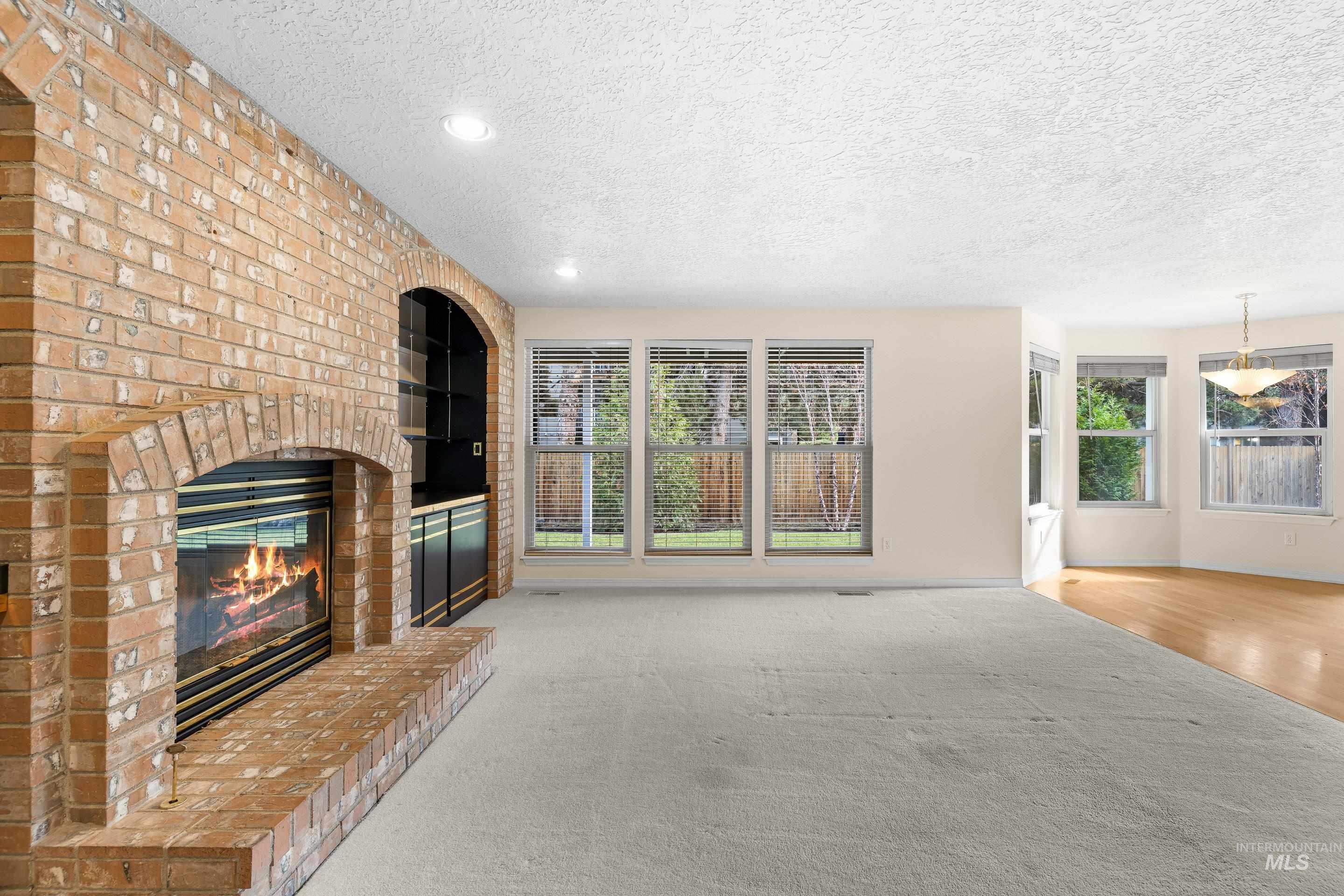 Unfurnished living room with a textured ceiling, built in features, carpet flooring, a fireplace, and recessed lighting