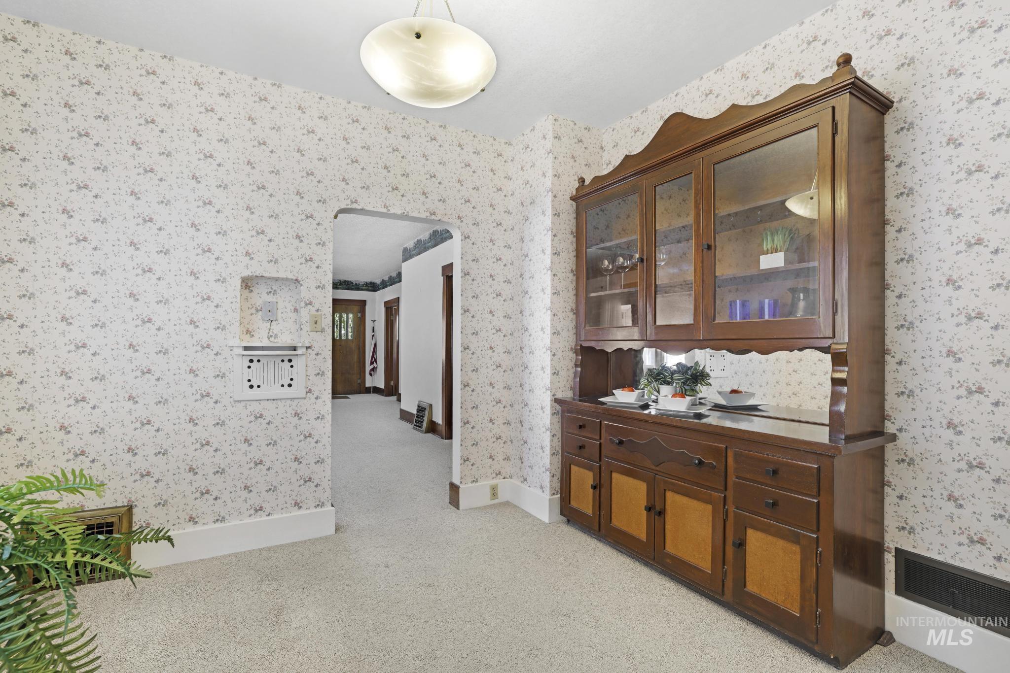 Hall with light colored carpet and wallpapered walls