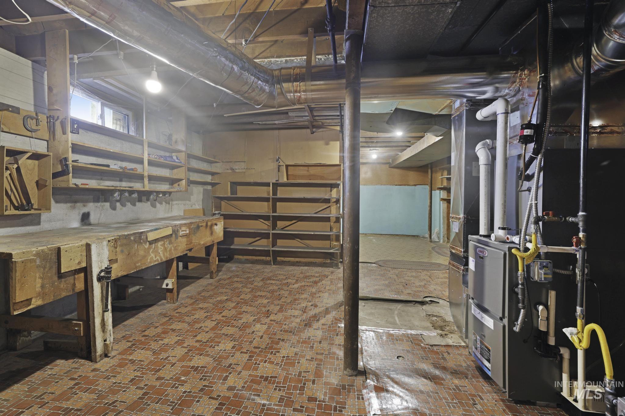 Unfinished basement featuring heating unit and a workshop area