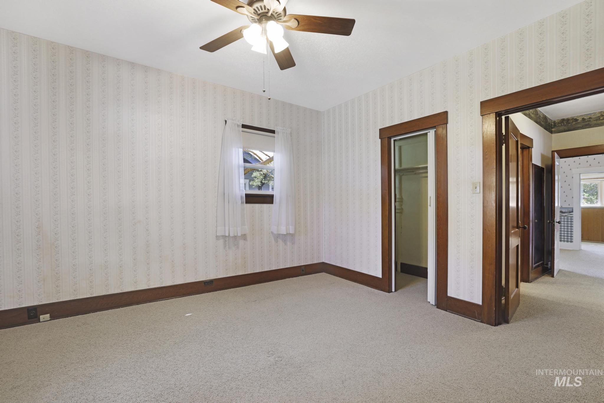 Unfurnished bedroom with multiple windows, ceiling fan, and carpet flooring