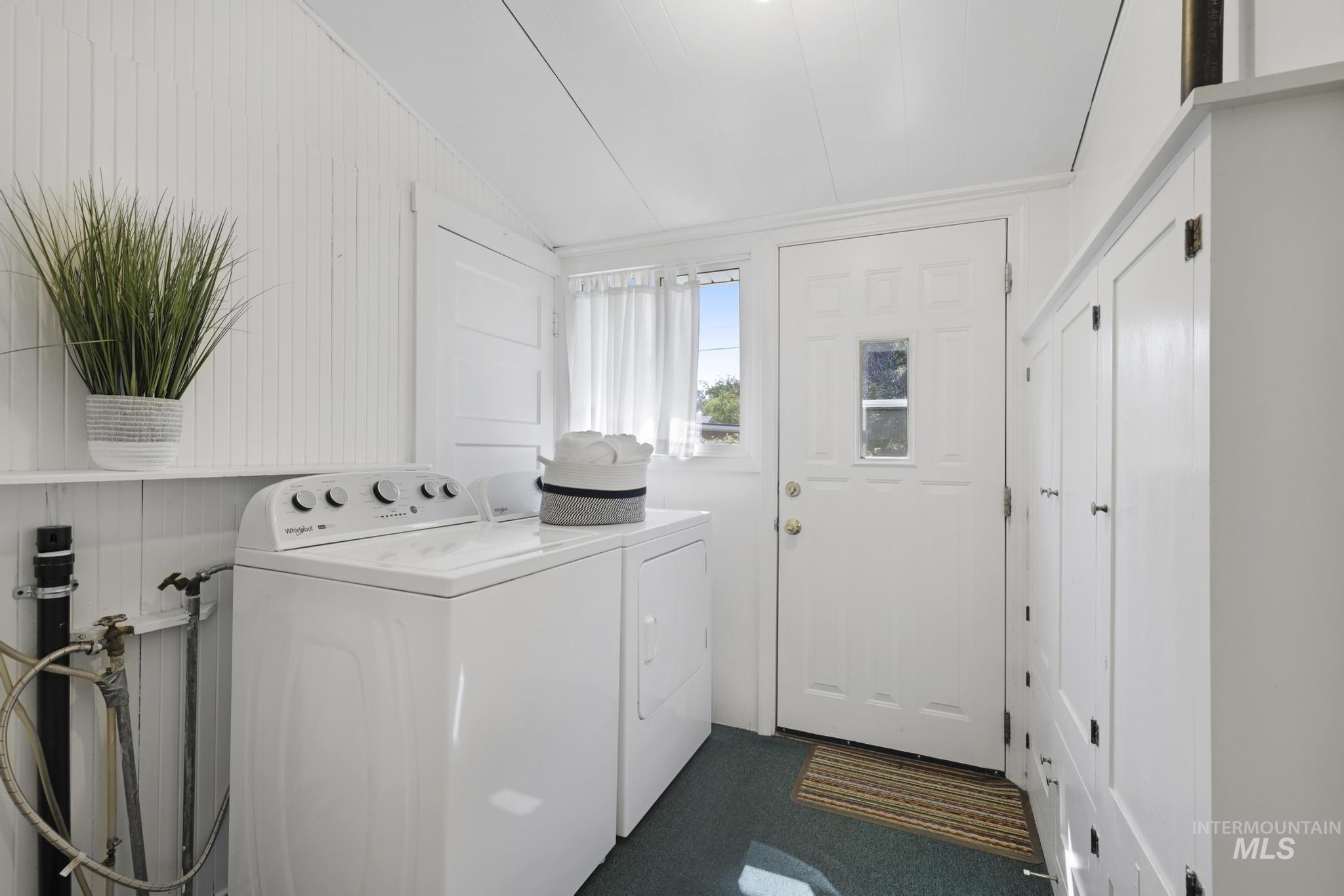 Laundry area with wood walls, dark colored carpet, and independent washer and dryer